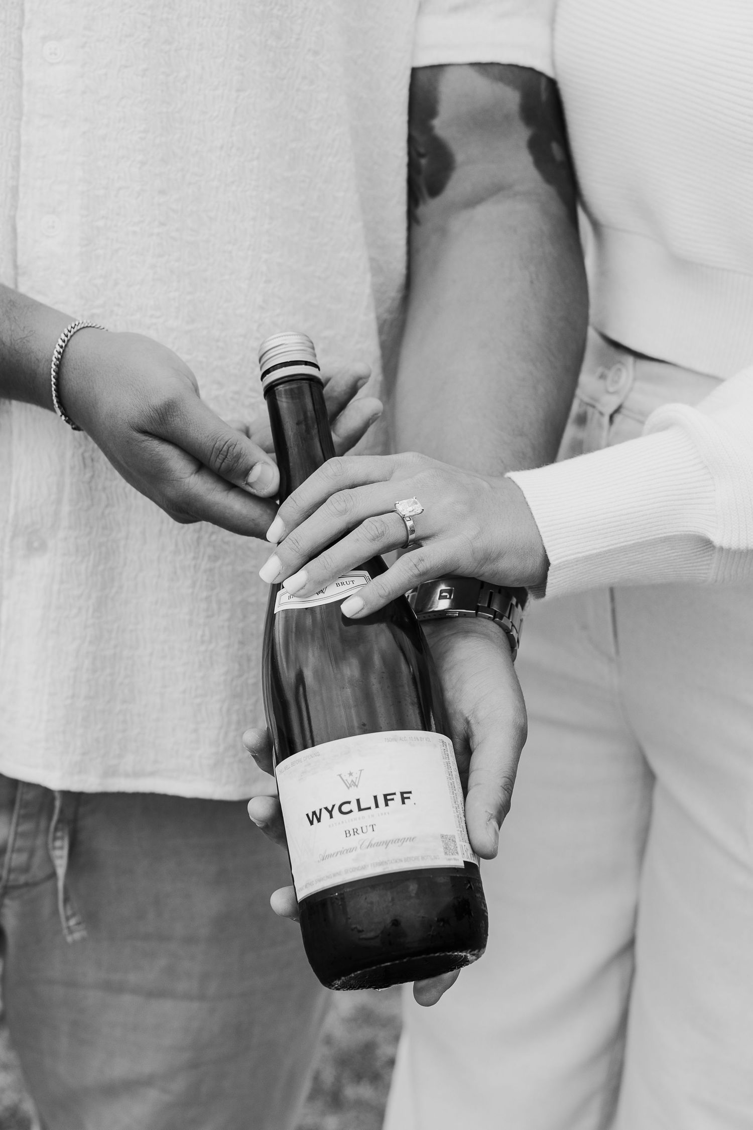 Black and white photos showcase hands holding a Wycliff wine bottle against a light background.