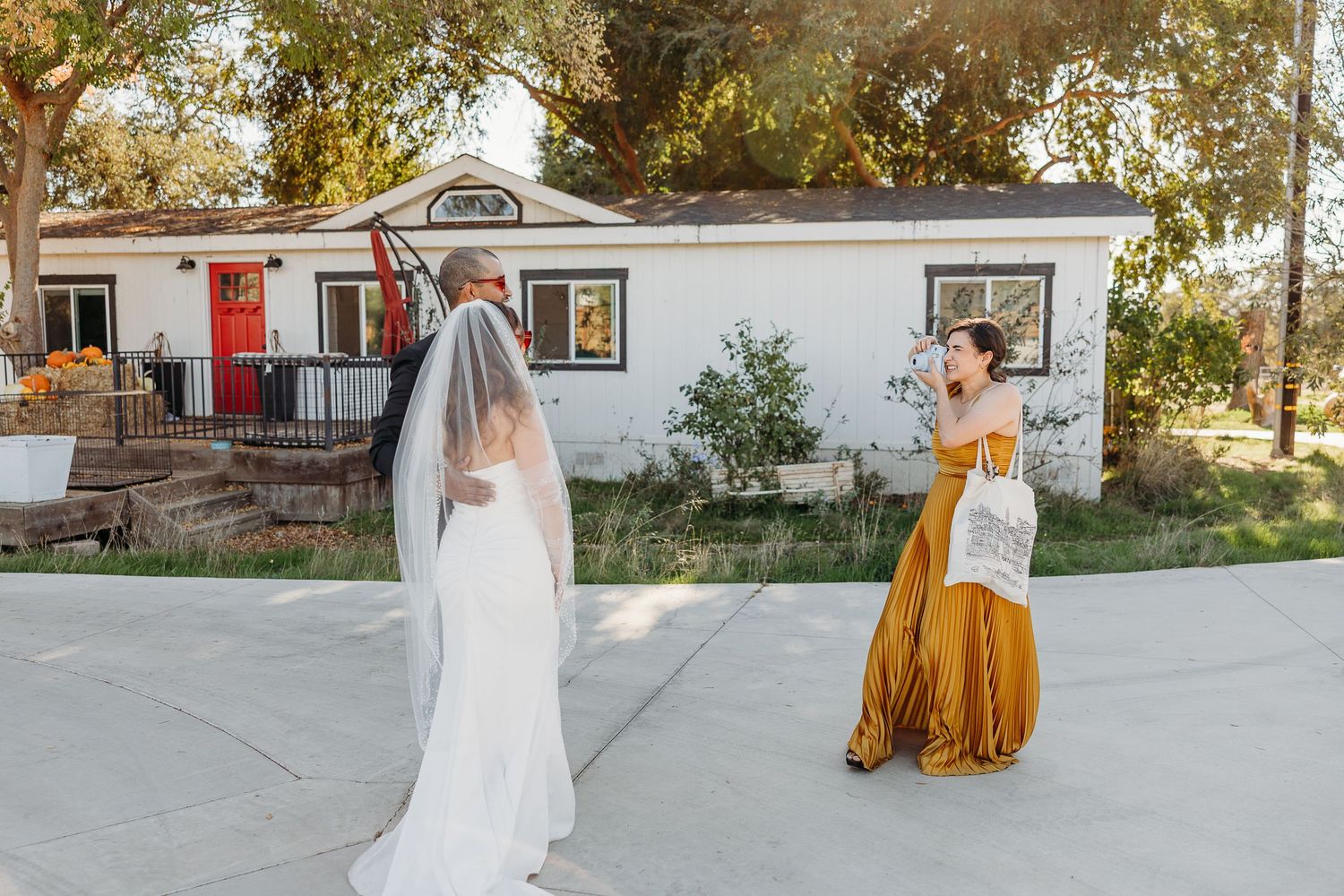 Outdoor wedding venue with white building and red accents in the background.