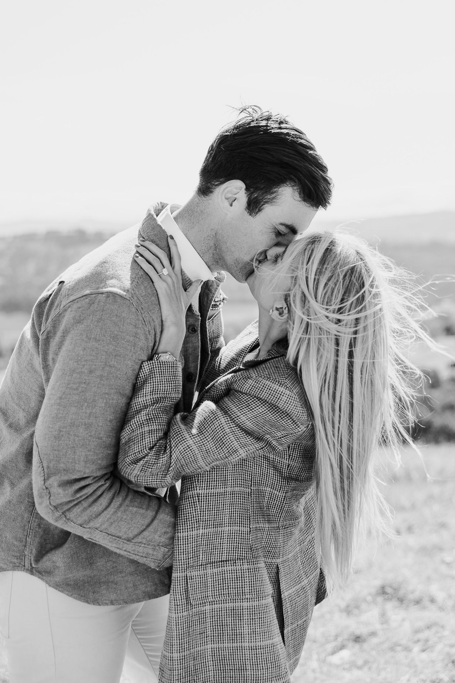 Black and white photo capturing a tender moment between two people in a natural setting.