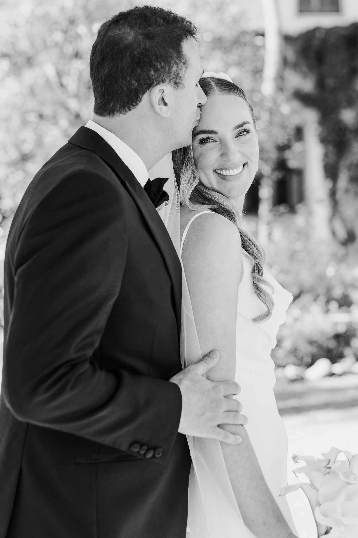 A romantic black and white portrait of a couple on their wedding day showing a tender moment together.