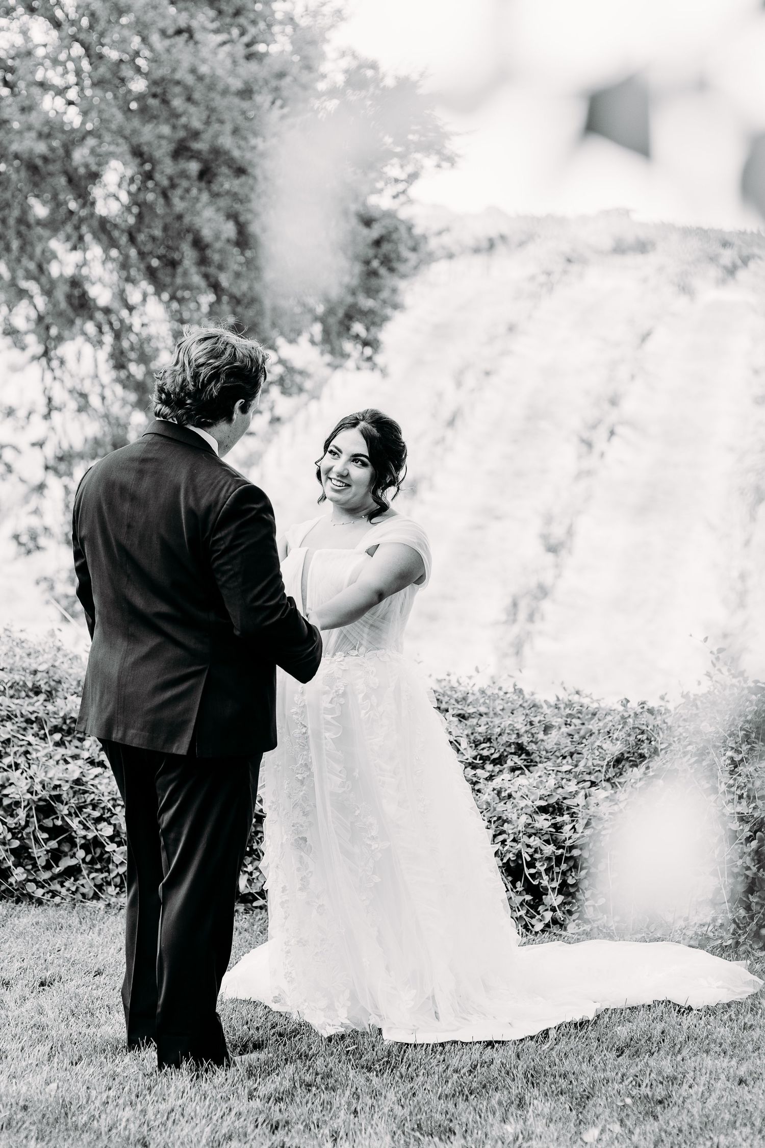 Black and white portrait of a couple in wedding attire sharing an intimate moment outdoors.