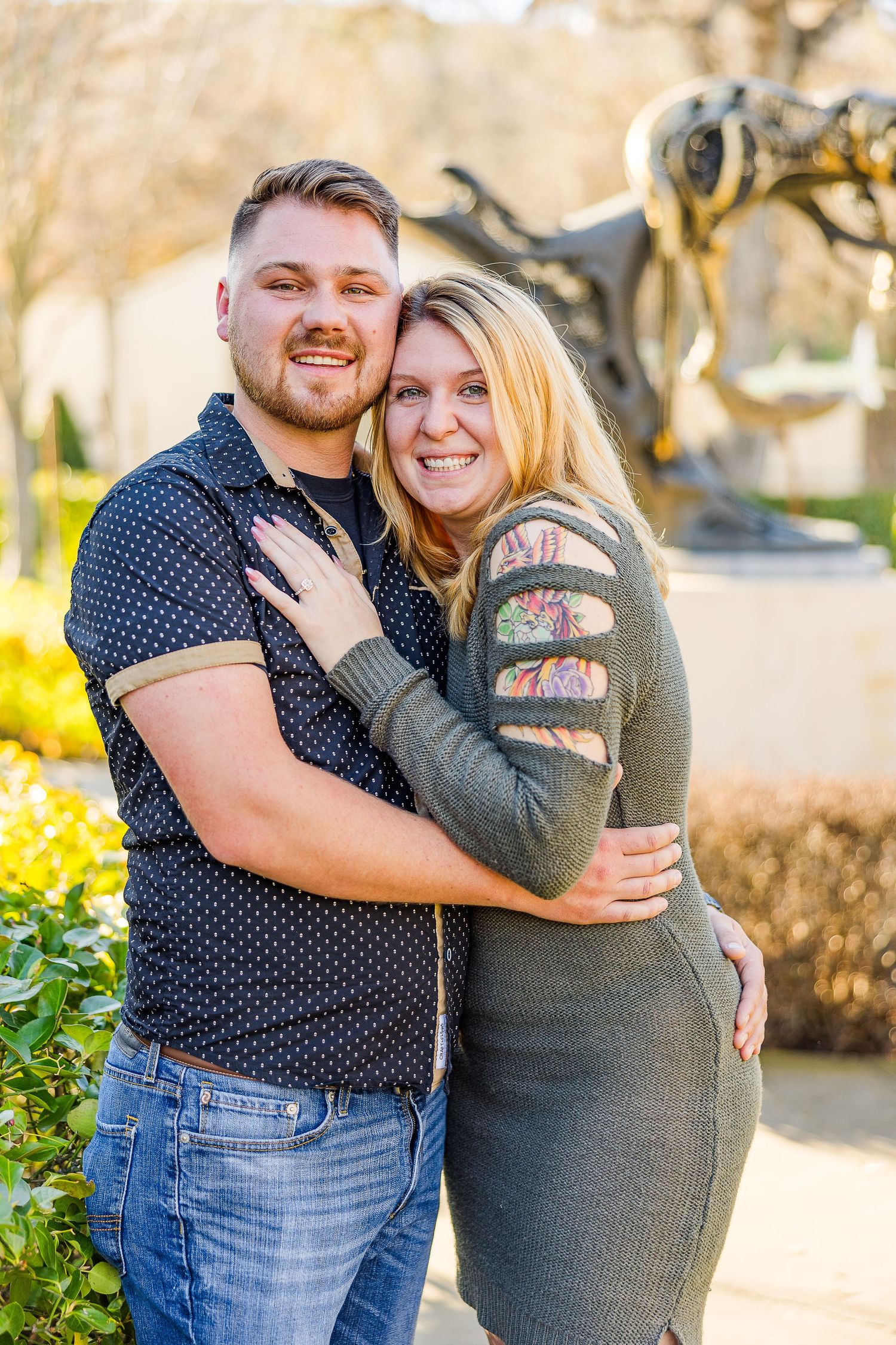 Happy couple poses for a portrait in a sunny garden with decorative landscaping.