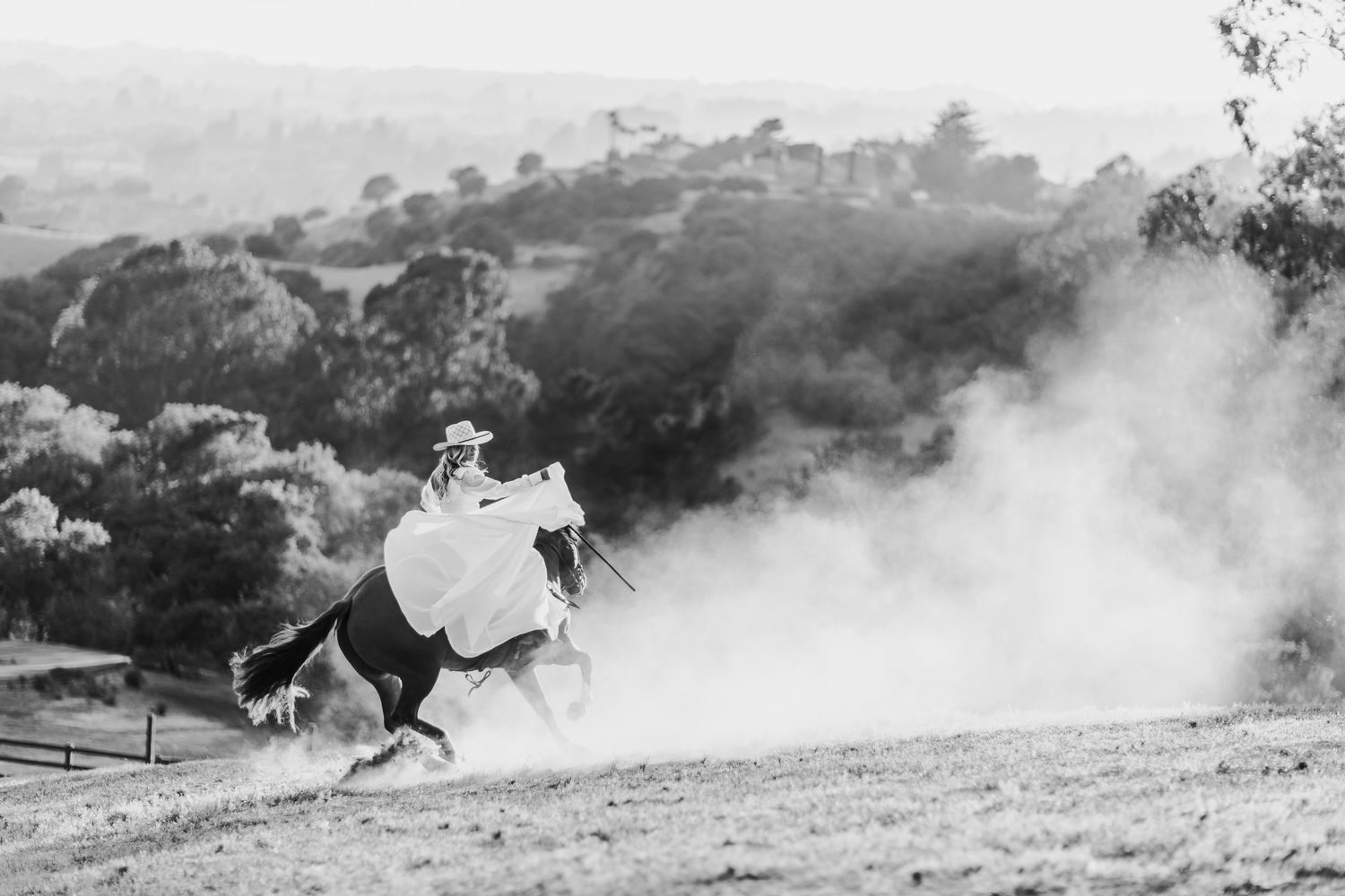 Two riders on horseback silhouetted against misty hills in black and white photography.