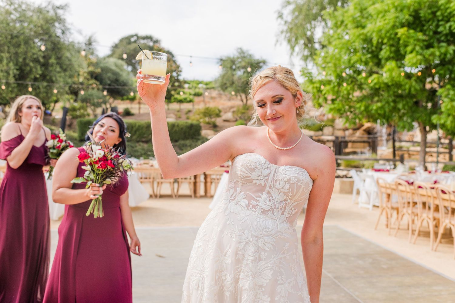 Celebratory moment at outdoor wedding reception with burgundy bridesmaid dresses.
