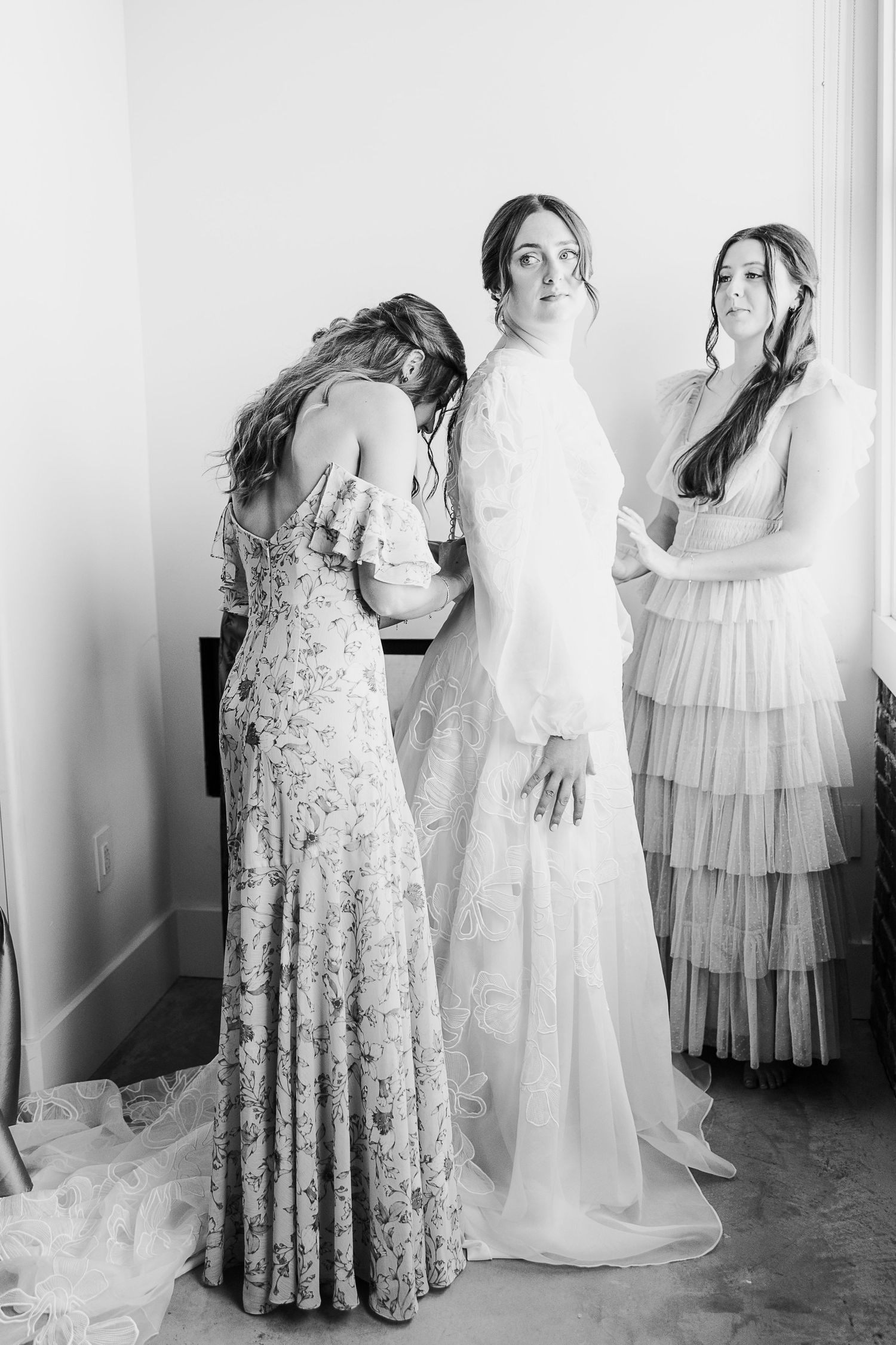 Black and white photo of wedding dress preparations with flowing gowns and elegant details.