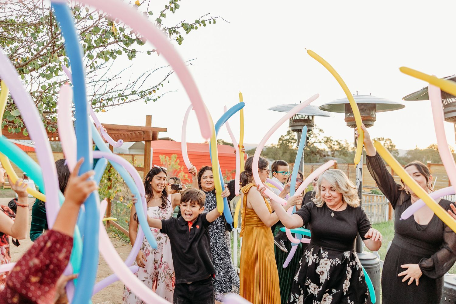 Wedding guests waving colorful ribbon wands during an outdoor celebration.