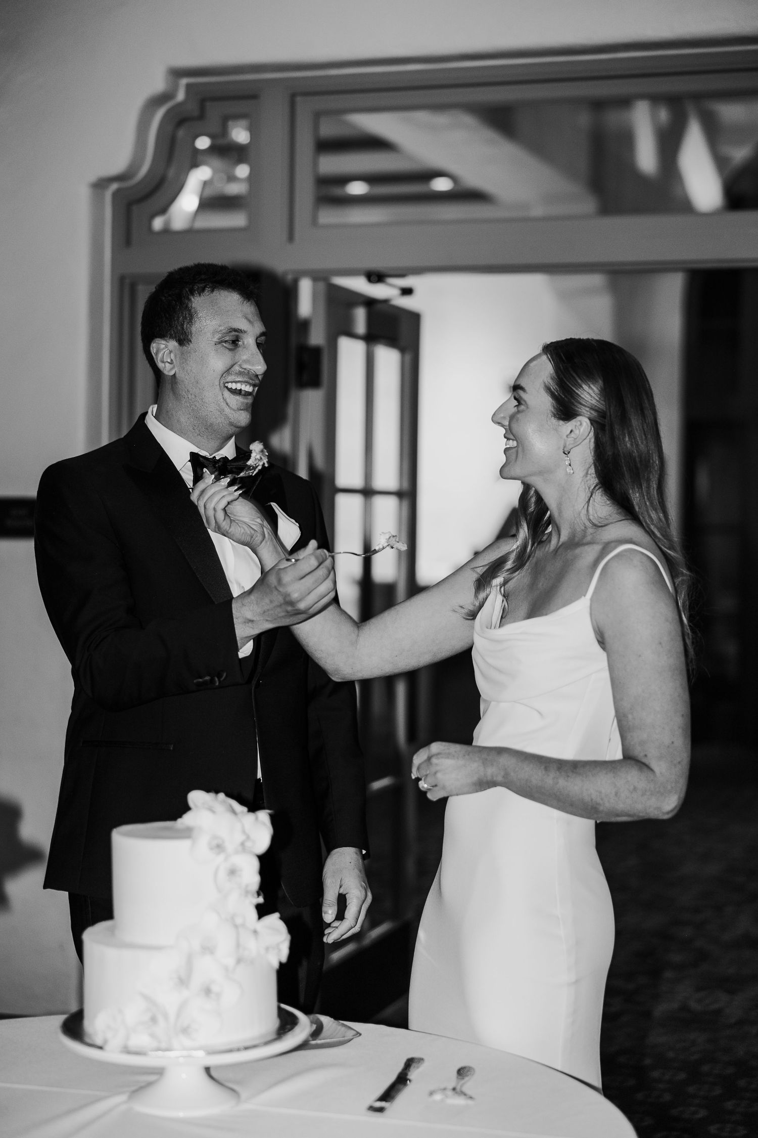 Wedding cake cutting sequence shows playful moment between newlyweds.