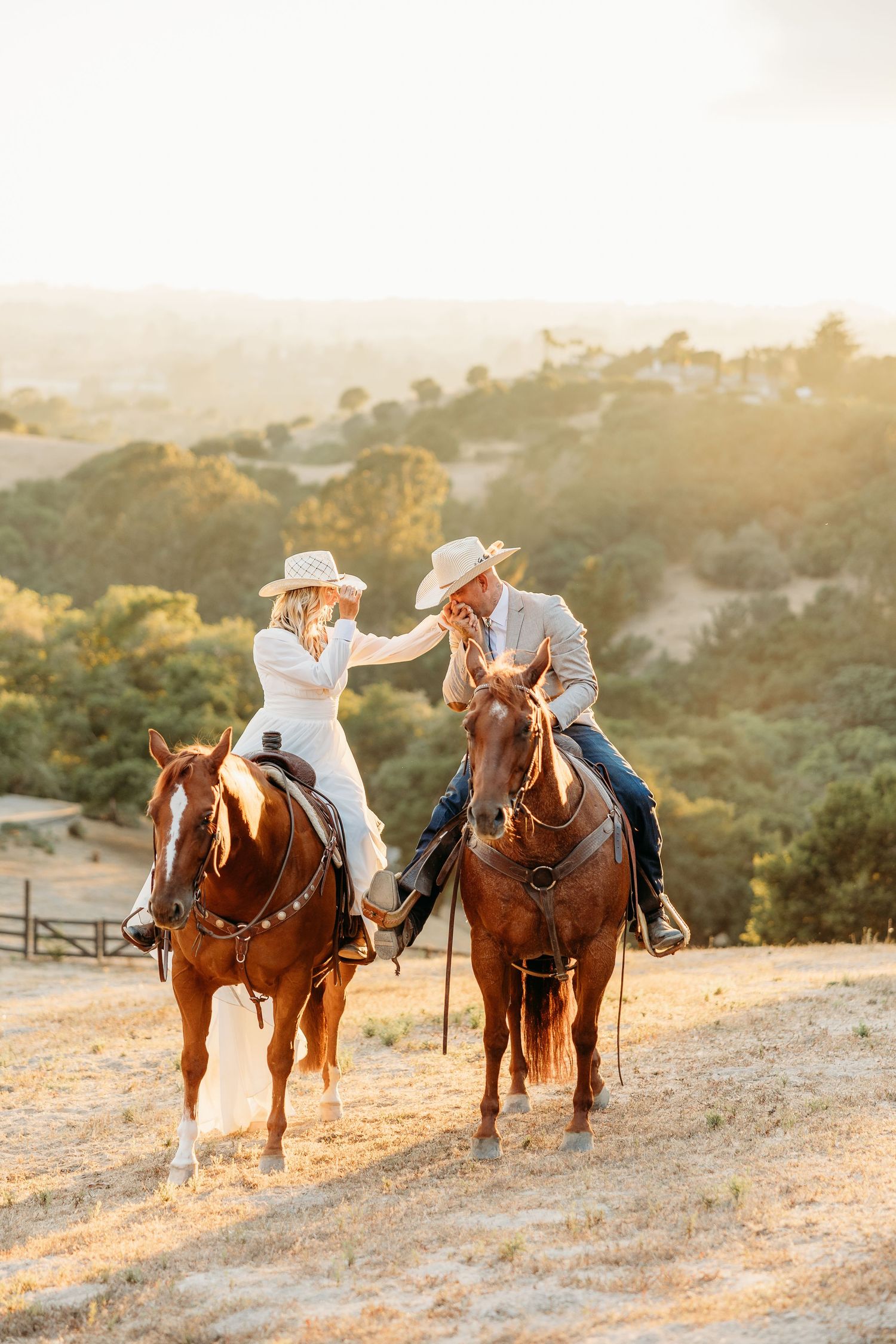 Two riders on horseback sharing a moment during golden hour in the hills.
