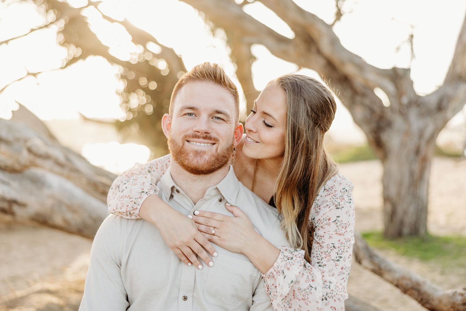 Loving embrace captured in warm sunlight with natural backdrop.