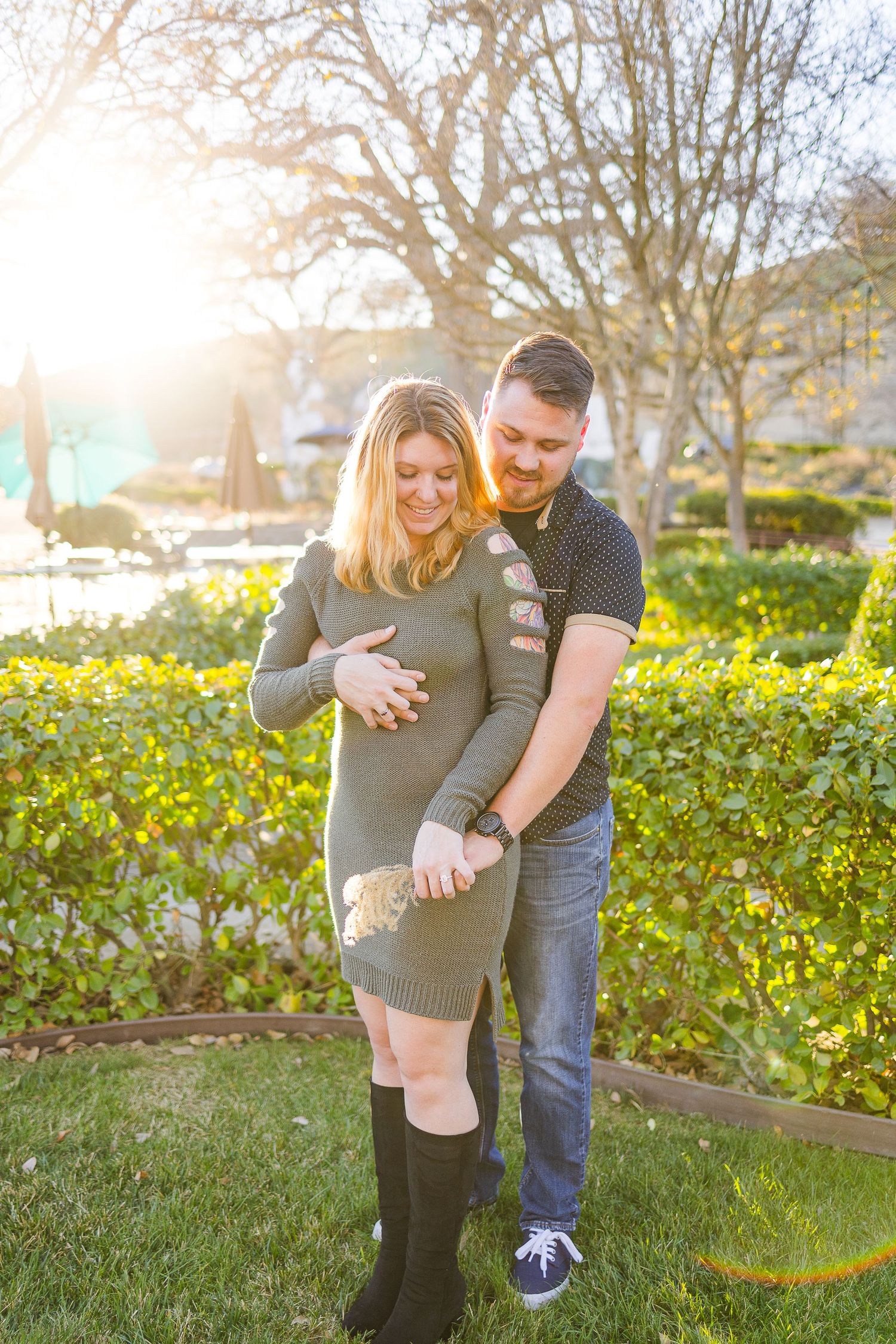 A couple shares an intimate moment while standing in a garden during sunset.