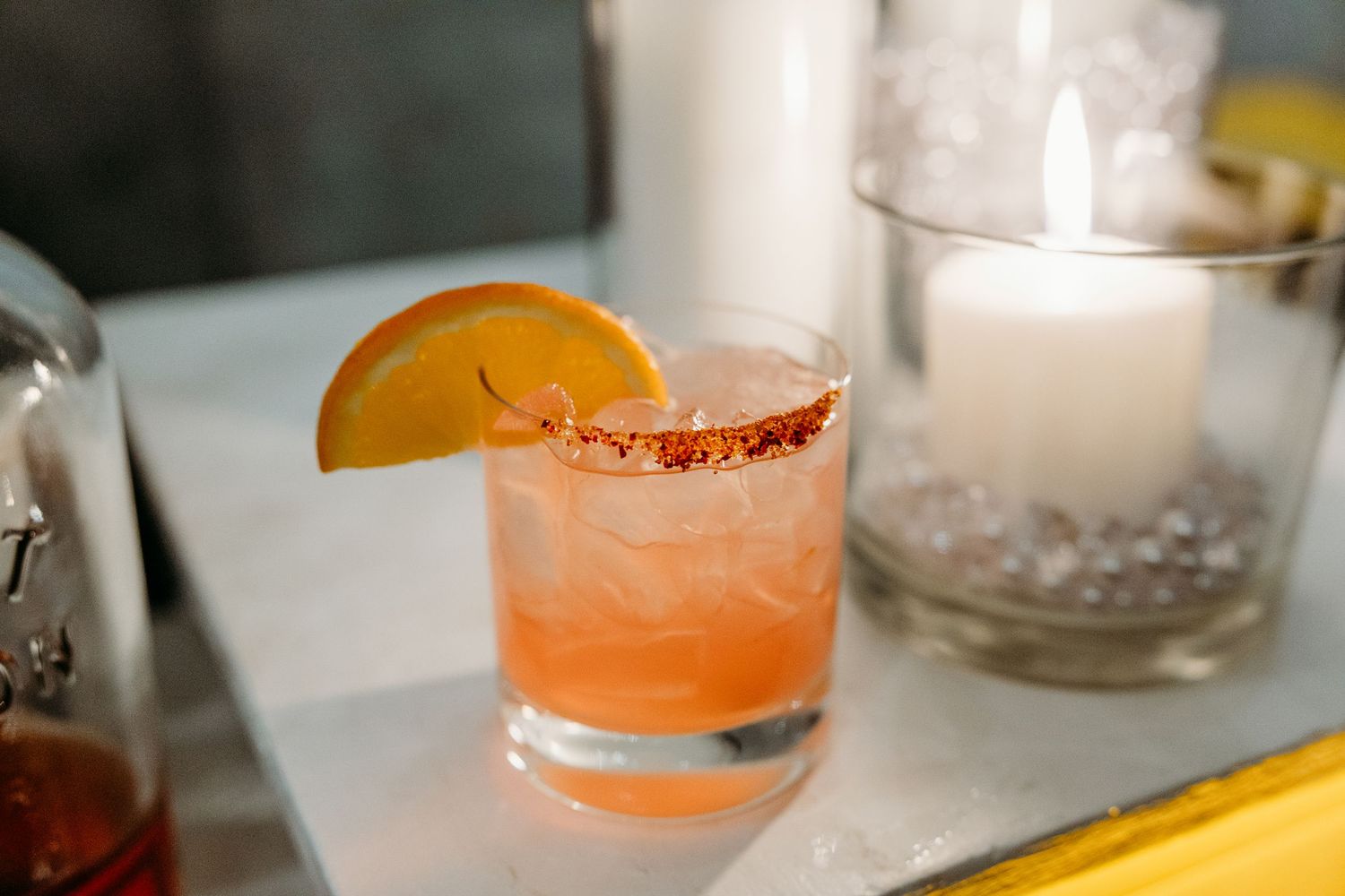 Cocktail garnished with orange slice on elegant bar setting.