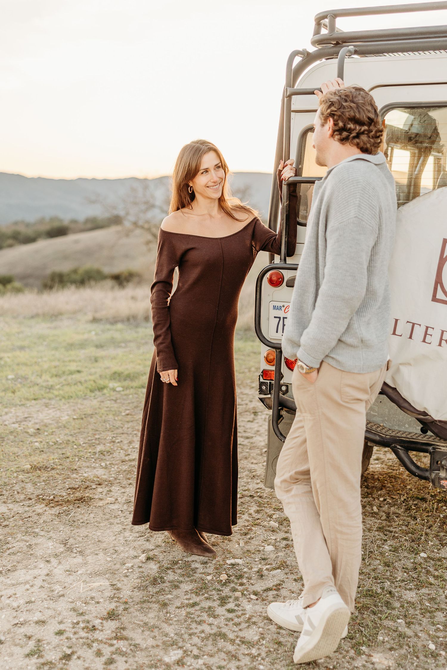 Couple poses casually by vintage vehicle during countryside photoshoot.