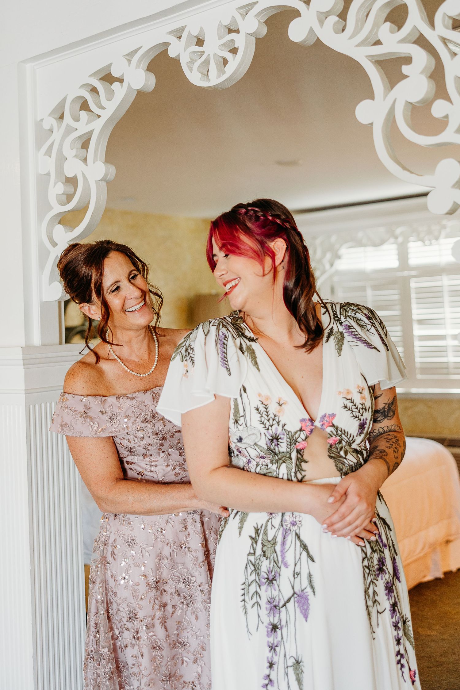 Wedding party members sharing emotional moments under ornate white archways.