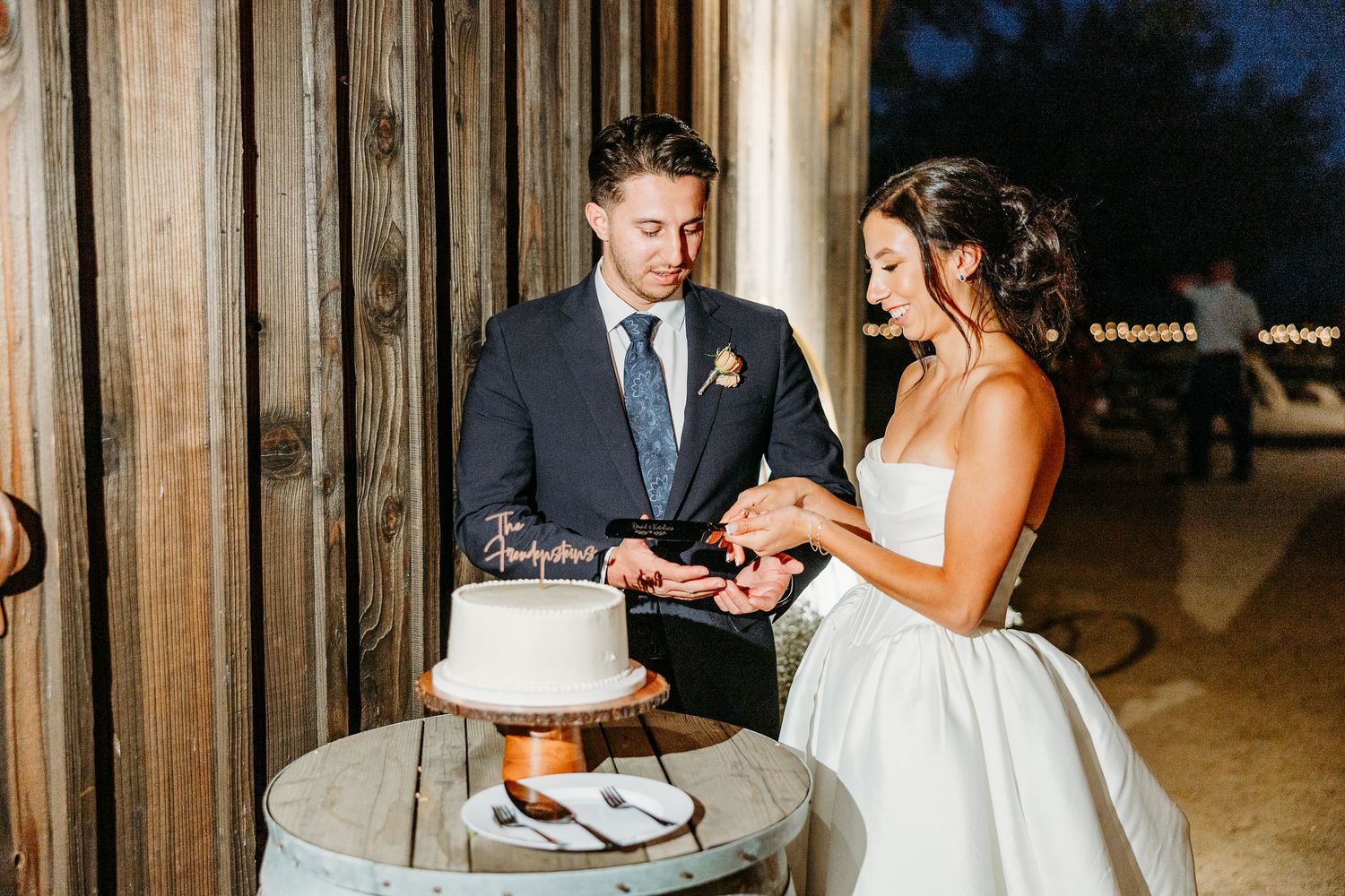 Couple cutting their wedding cake together during evening reception.