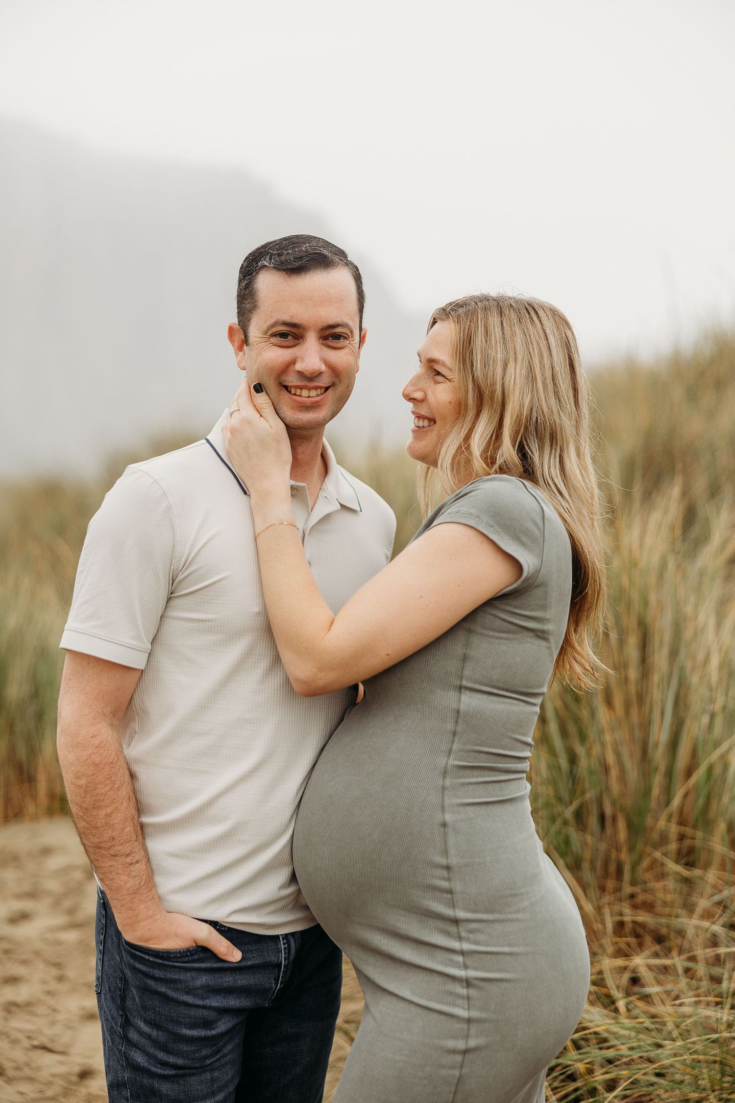 Candid maternity photo captures couple laughing together outdoors.