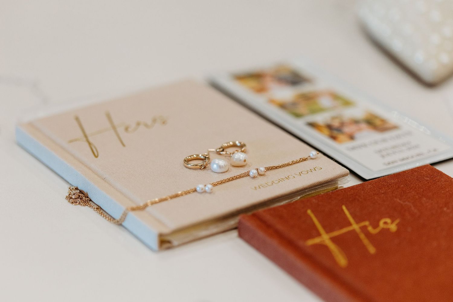 Close up of gold rings and vow books arranged on a light surface.