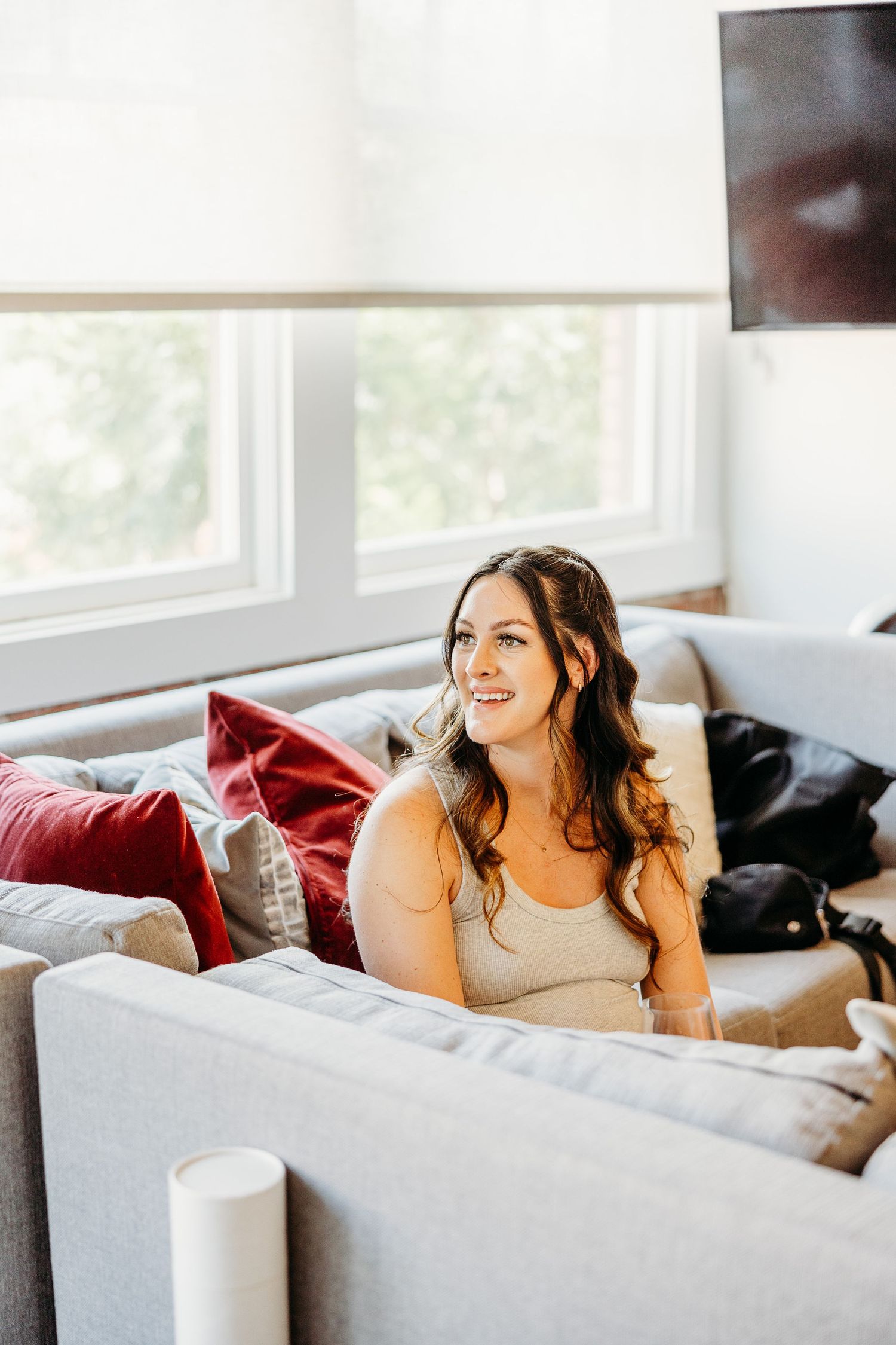 A relaxed and joyful moment as someone reclines on a gray couch in a bright sunlit room.