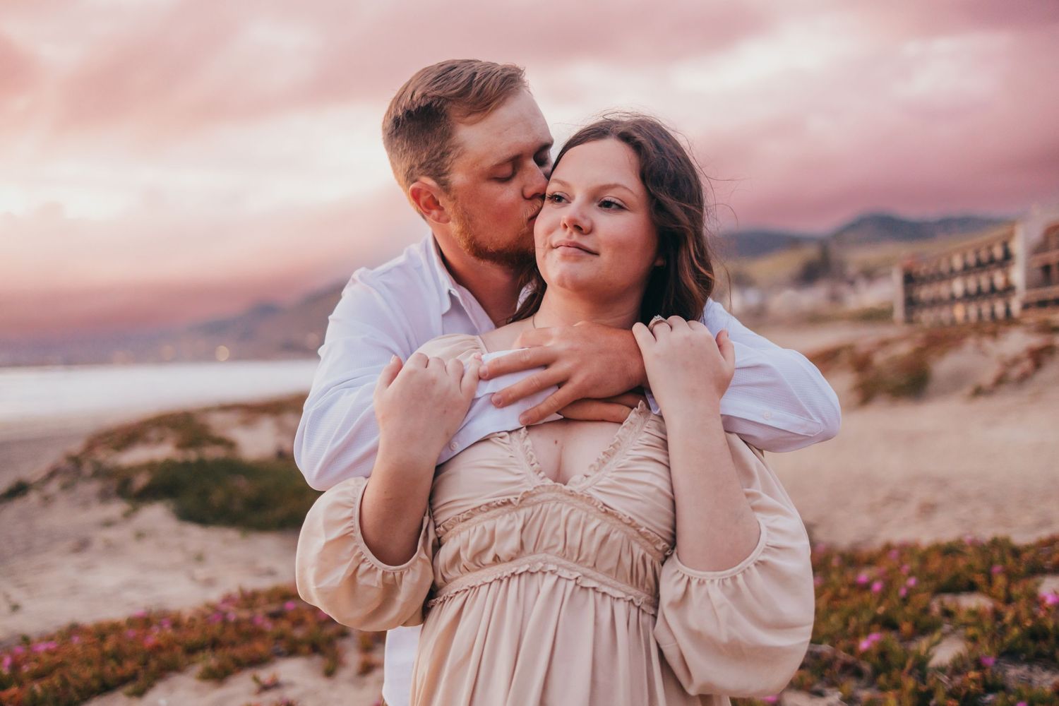 Intimate embrace captured during pink sunset on coastal desert cliffs.