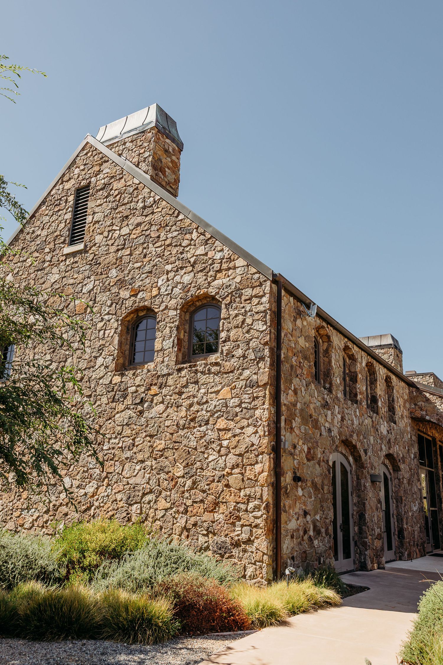 Historic stone building with arched windows and rustic architecture set against a bright blue sky.