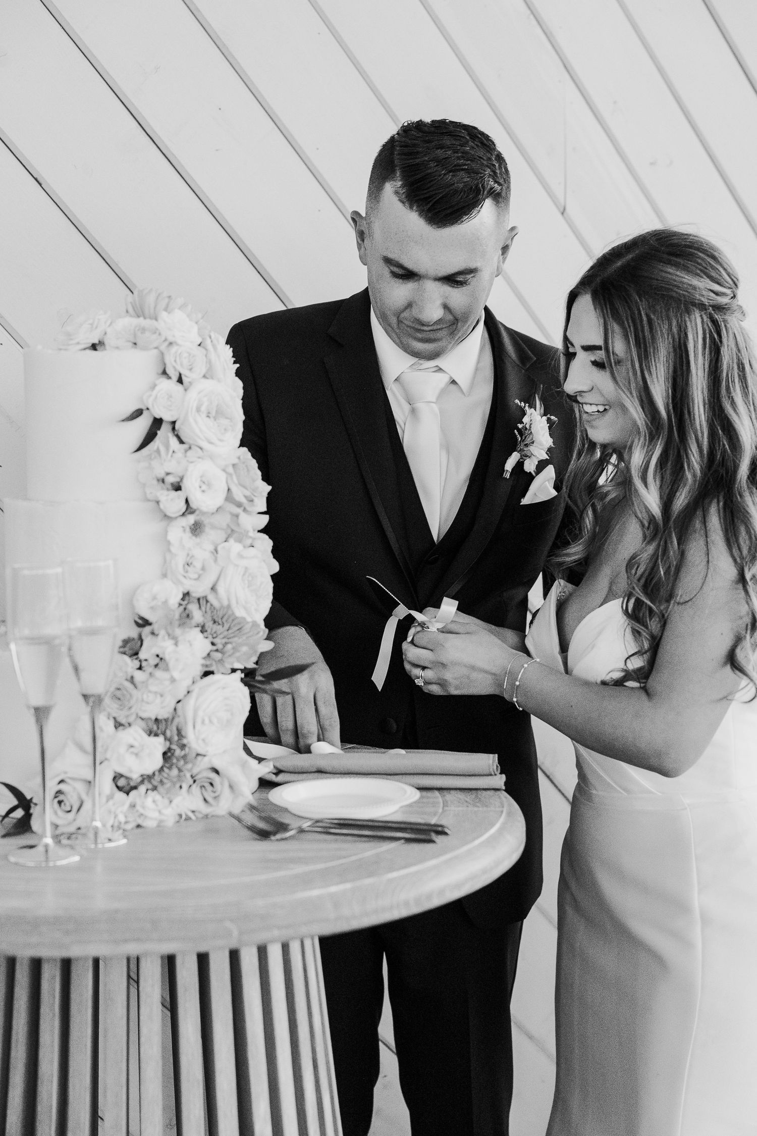 Black and white wedding reception photos show couple sharing intimate moments at a white-draped venue.