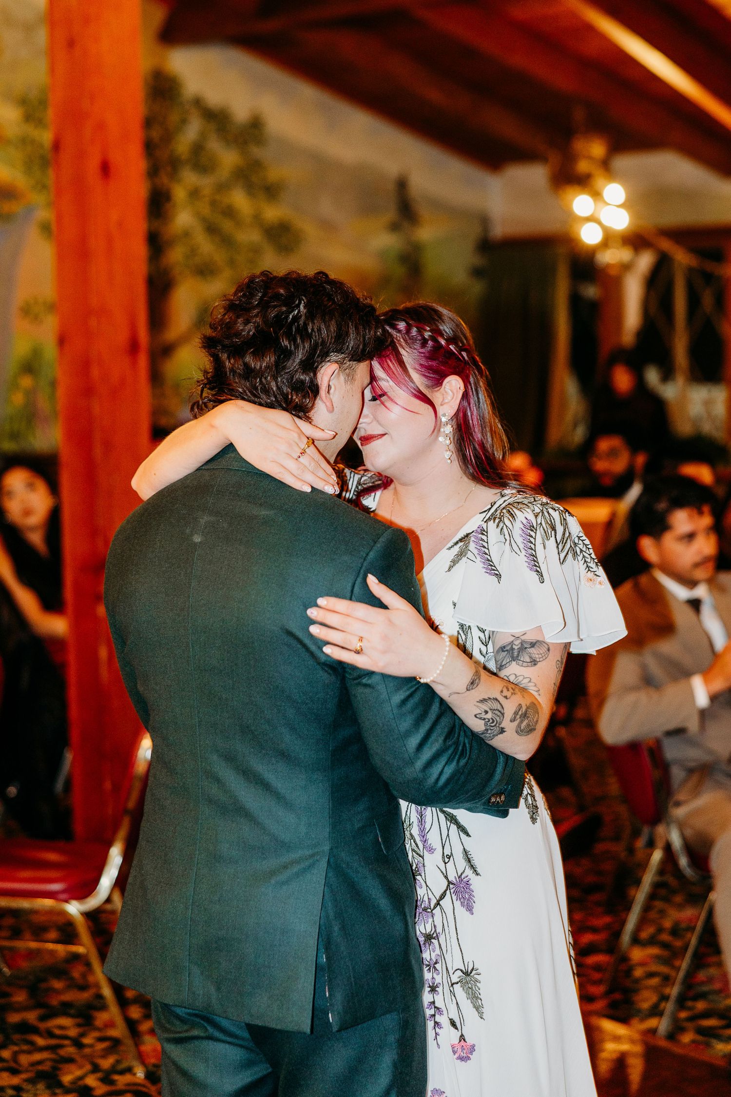 Couples share intimate dances under warm lighting at an indoor wedding reception.