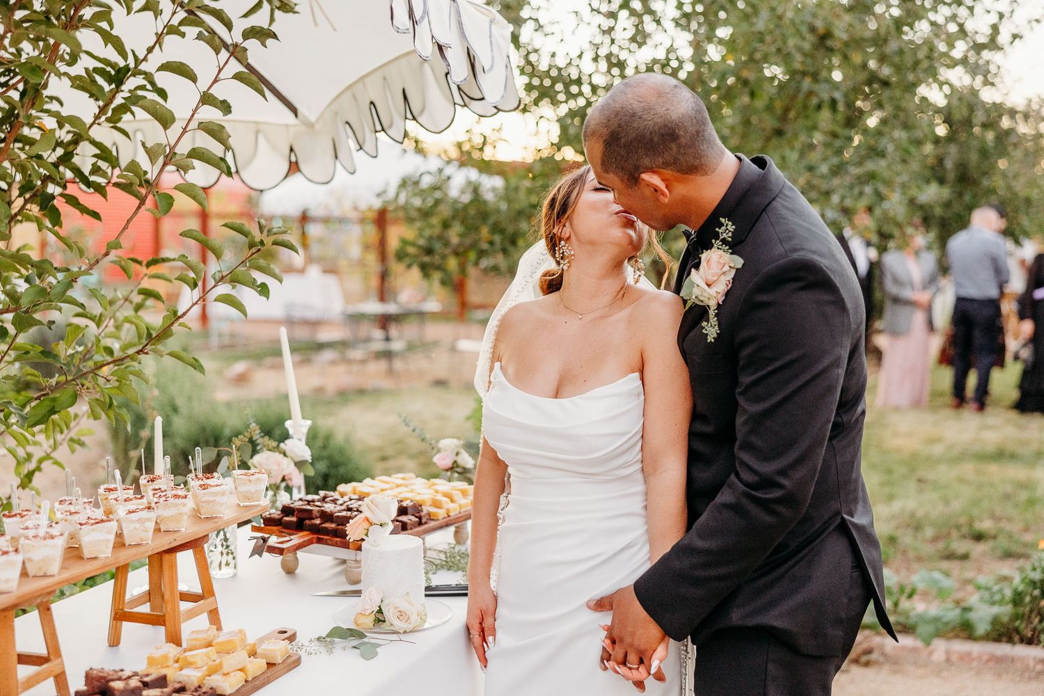 Outdoor wedding celebration with wooden chairs and natural decor under tree canopy.