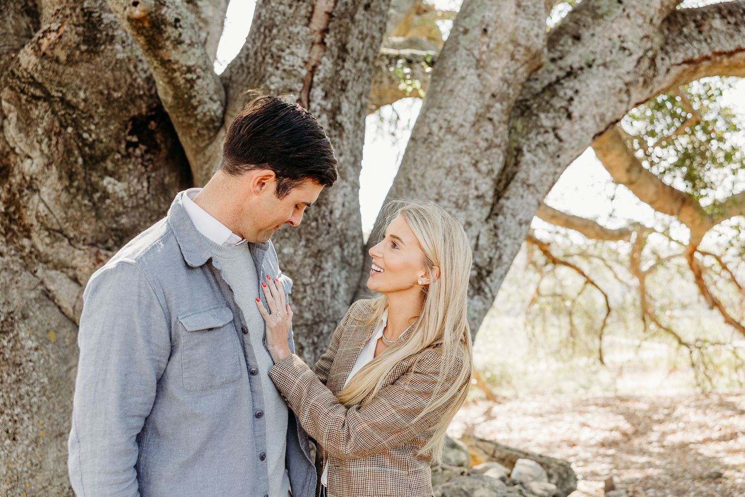 Candid interaction between couple among twisted tree branches in natural light.
