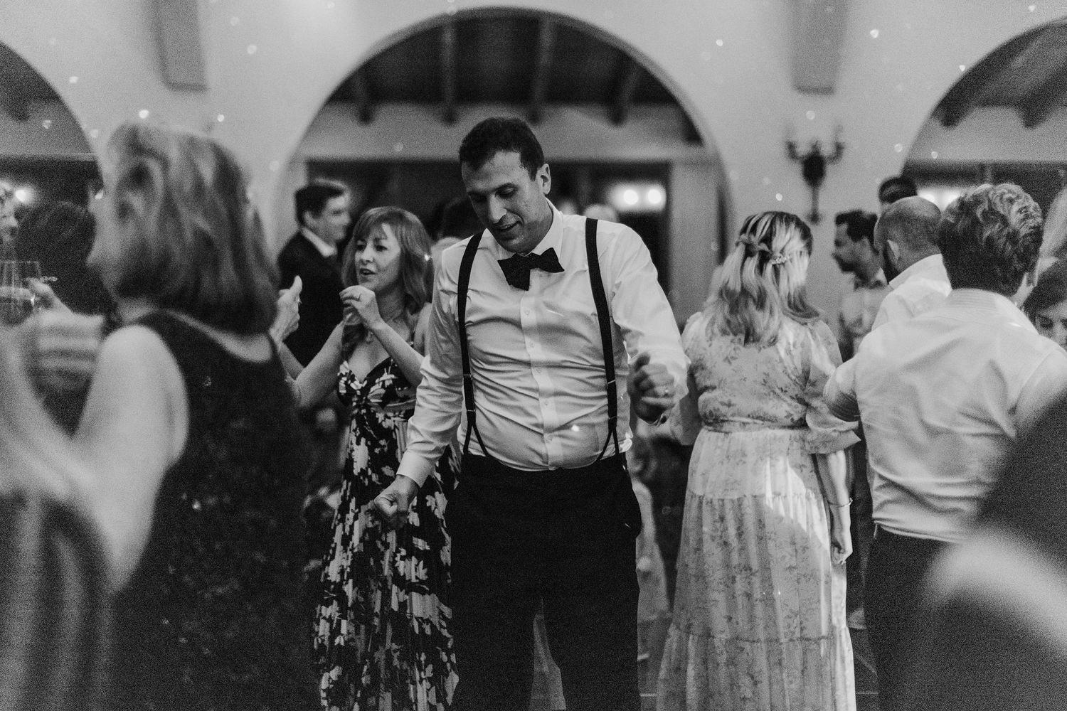 Wedding reception dance floor scene with guests celebrating in black and white.