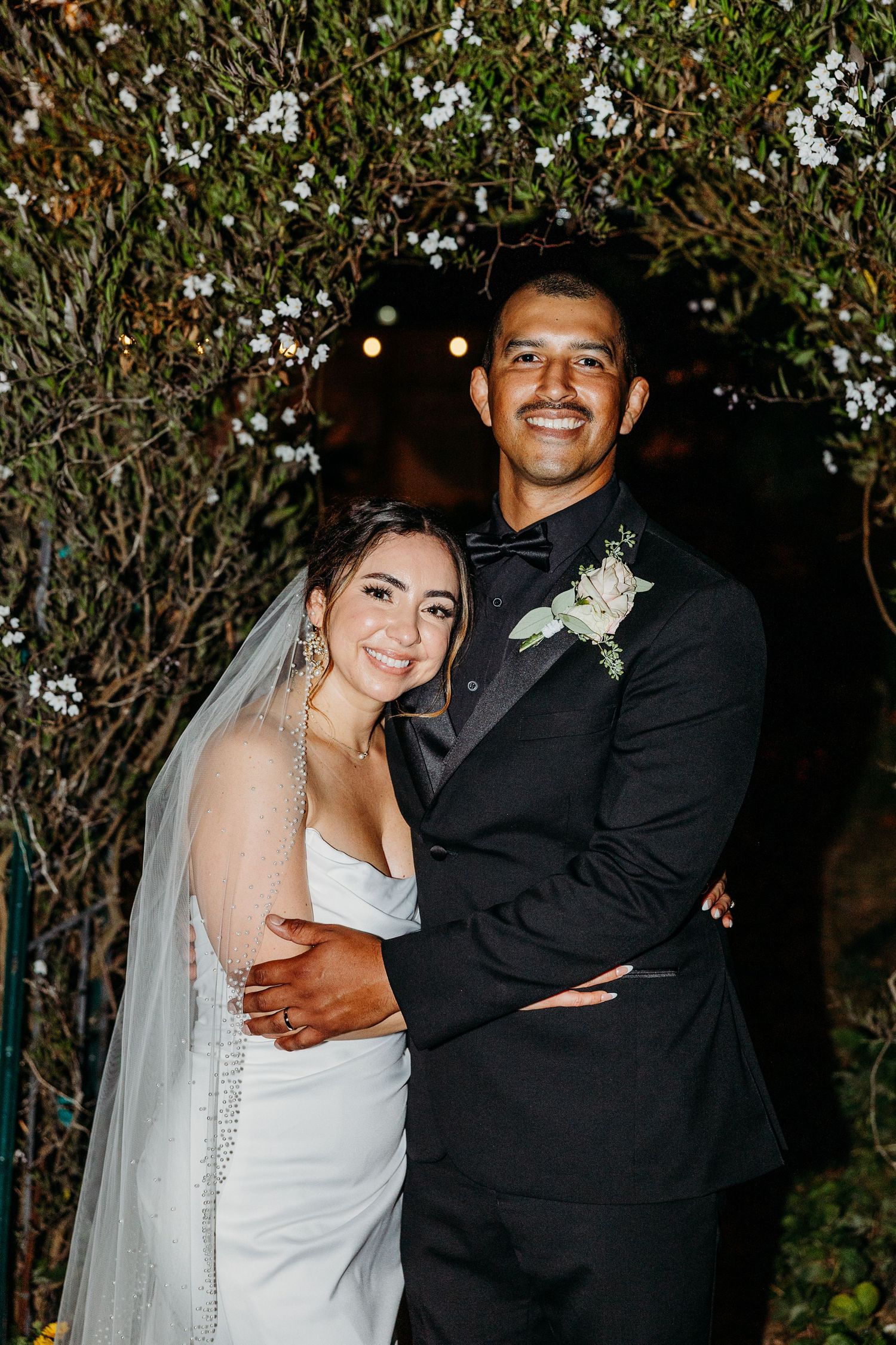 A happy bride and groom embrace and laugh together during their outdoor wedding celebration.