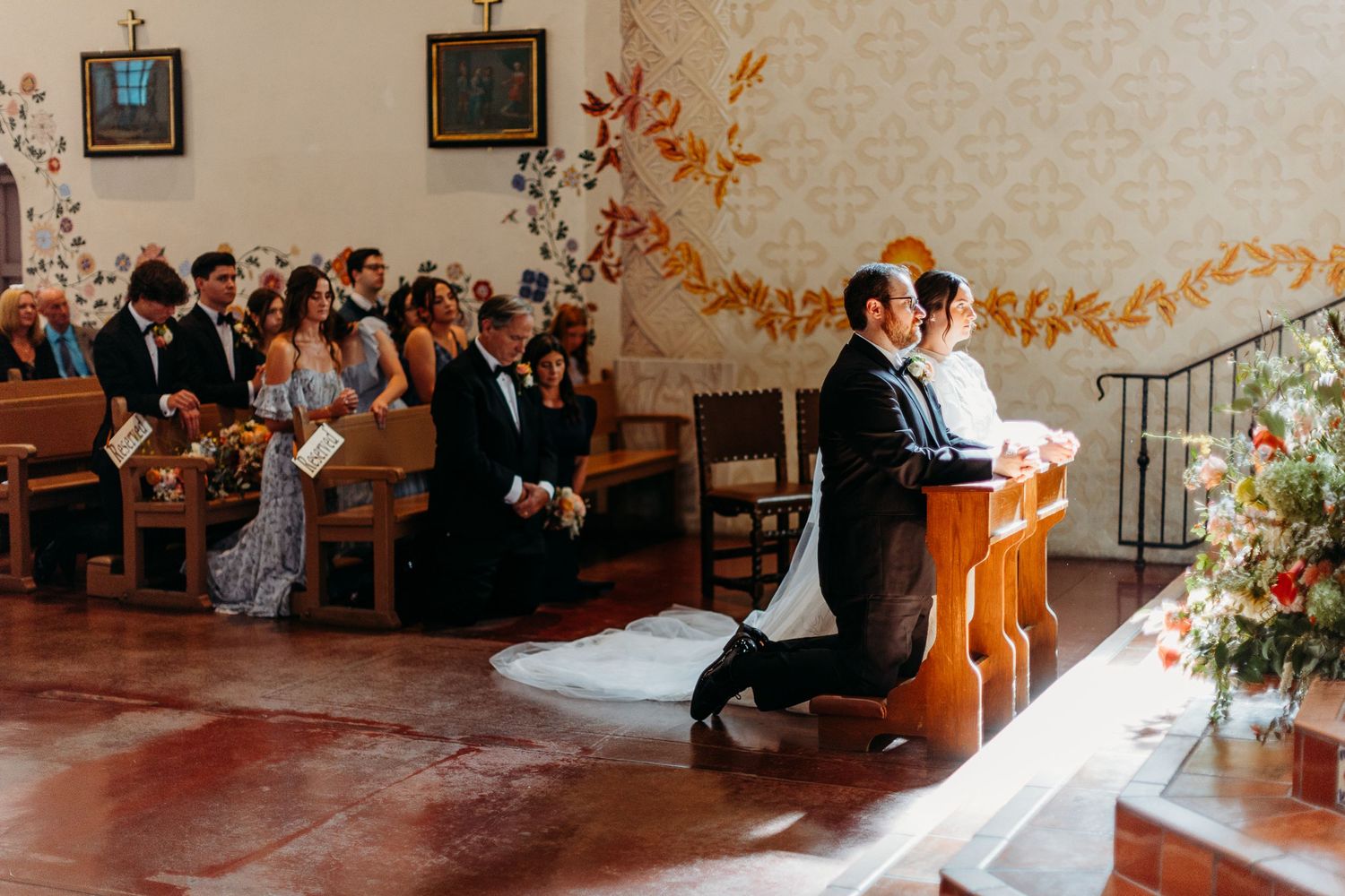 Wedding ceremony in traditional church with decorative fall garland and floral arrangements in Mission San Luis Obispo.