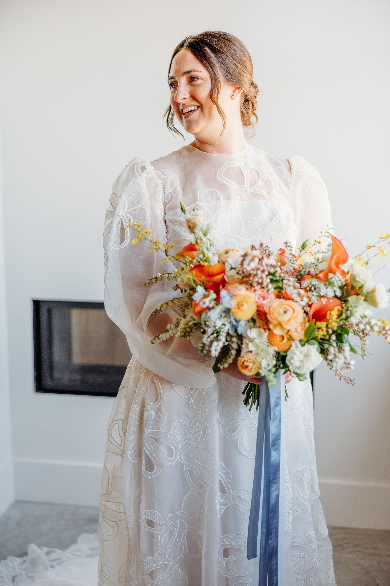 Bride in vintage-inspired lace gown holding colorful autumn wedding bouquet in Hotel Cerro SLO.