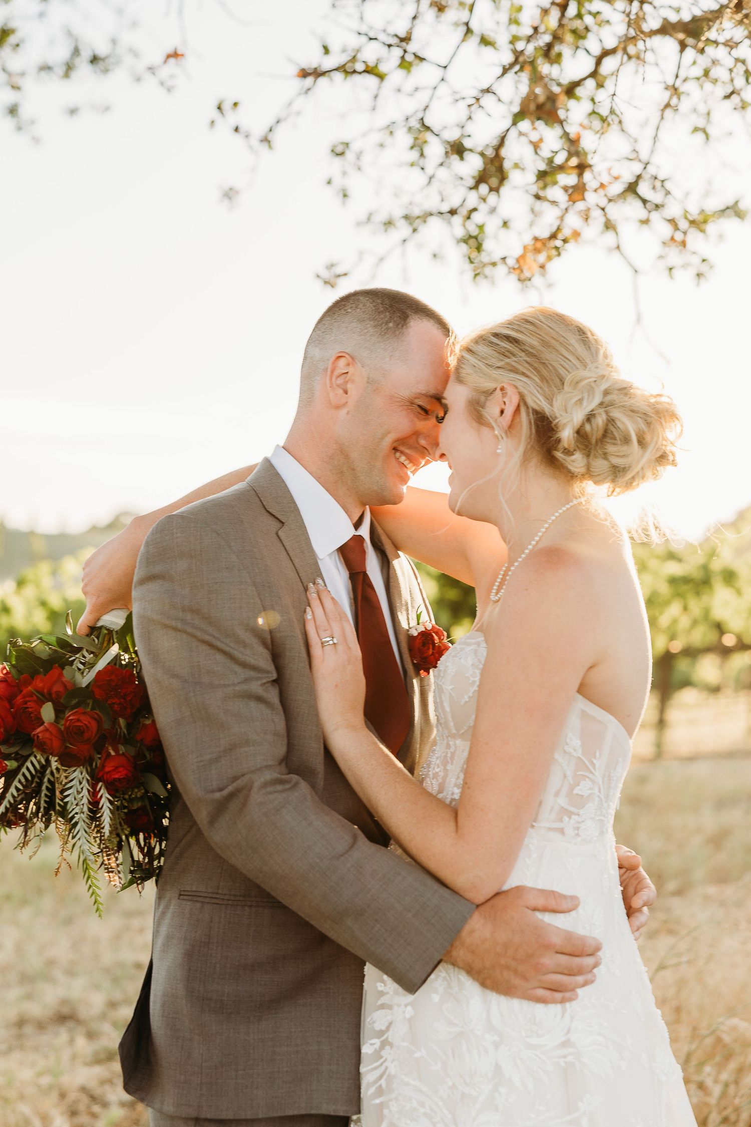 A joyful wedding couple sharing an intimate moment among vineyard rows.
