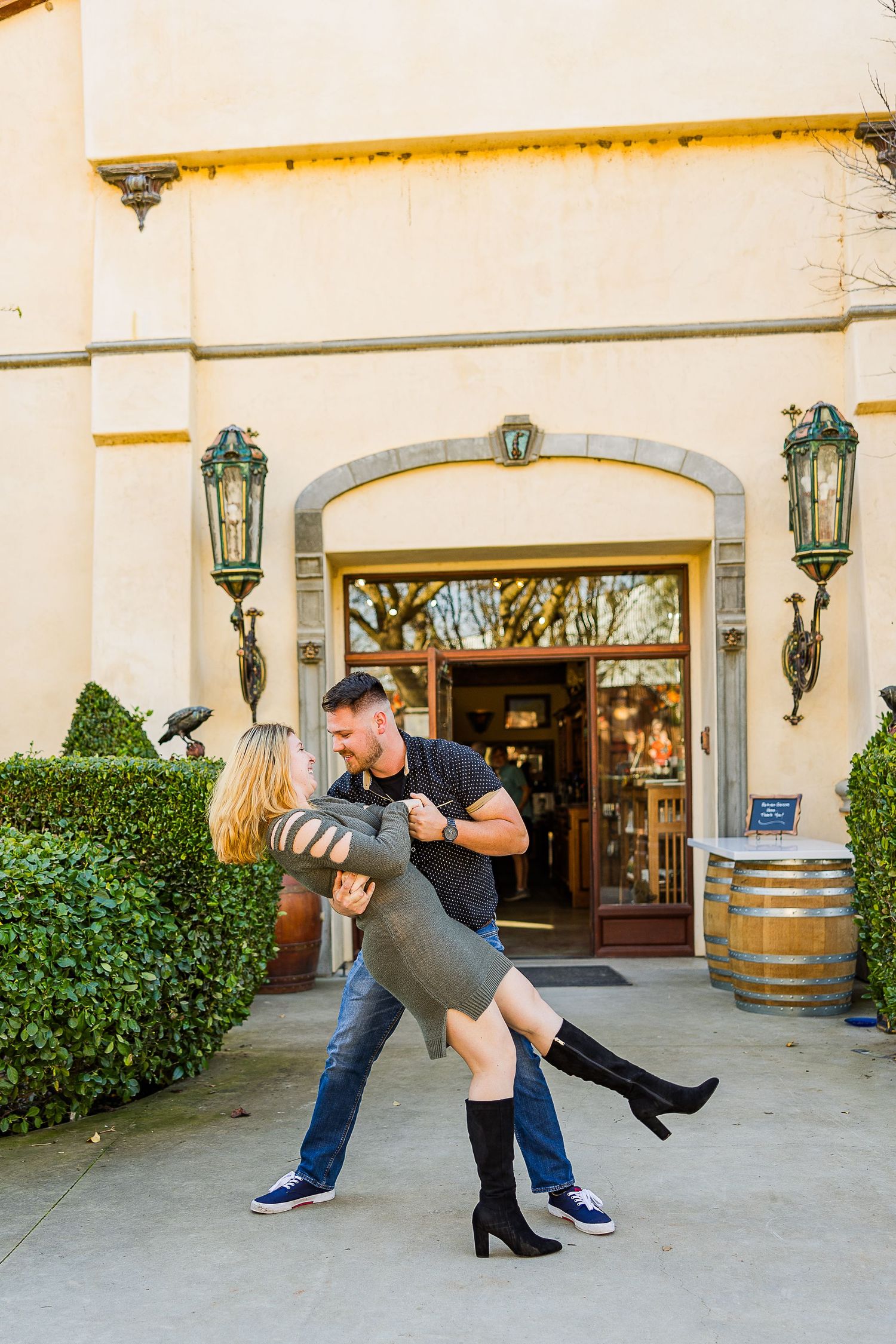 Couple dancing and dipping romantically in front of a Mediterranean-style building entrance with vintage lanterns.