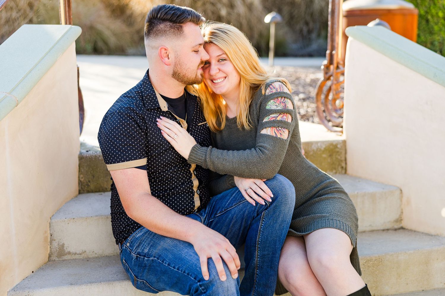 A couple laughs together during an outdoor photography session on concrete steps.