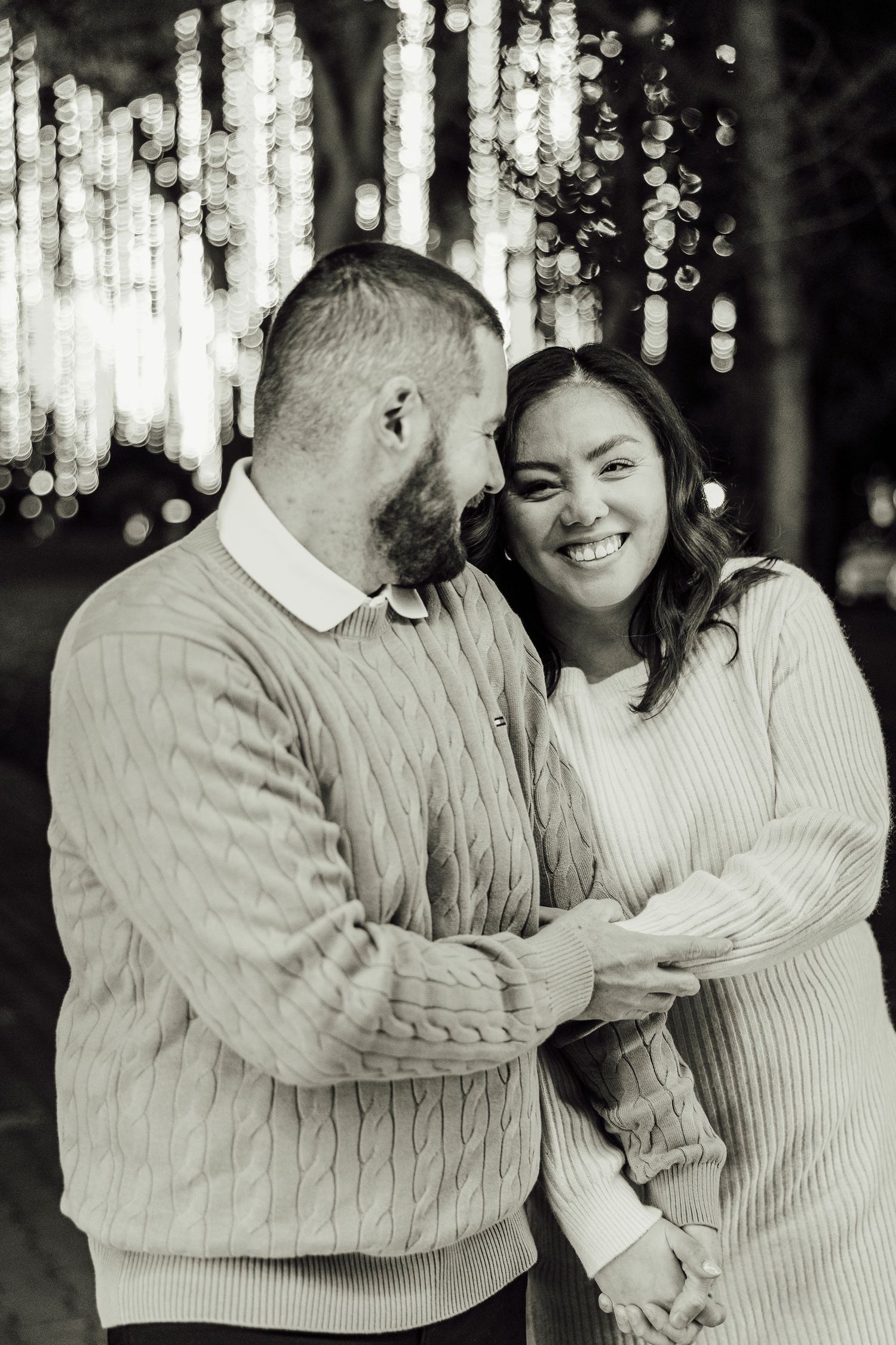 Black and white photo series showing a couple in matching sweaters sharing joyful moments together outdoors.