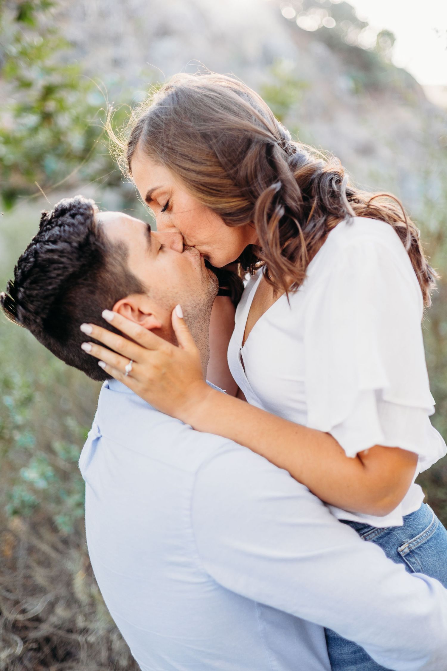 A romantic kiss shared between couple on hiking trail during golden hour.