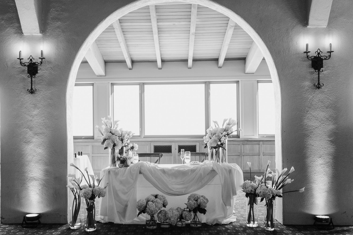 An elegant wedding reception setup with an arched doorway and white floral decorations.