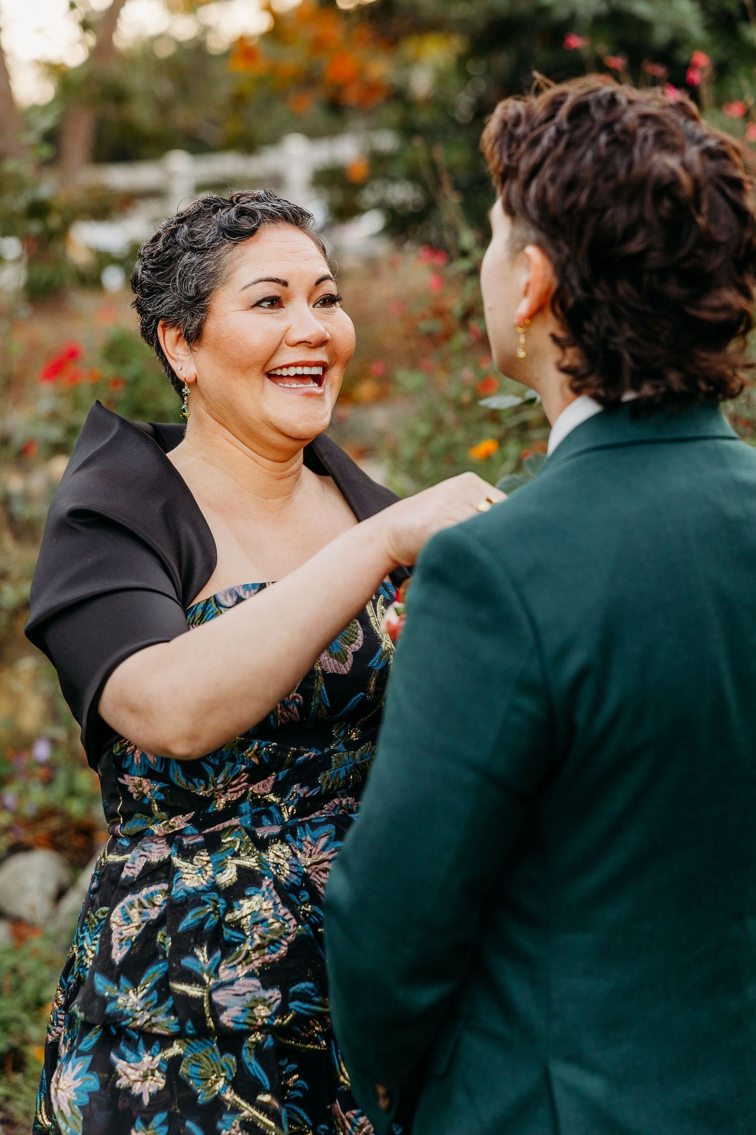 A joyful moment shared between wedding attendees wearing formal attire at an outdoor celebration.