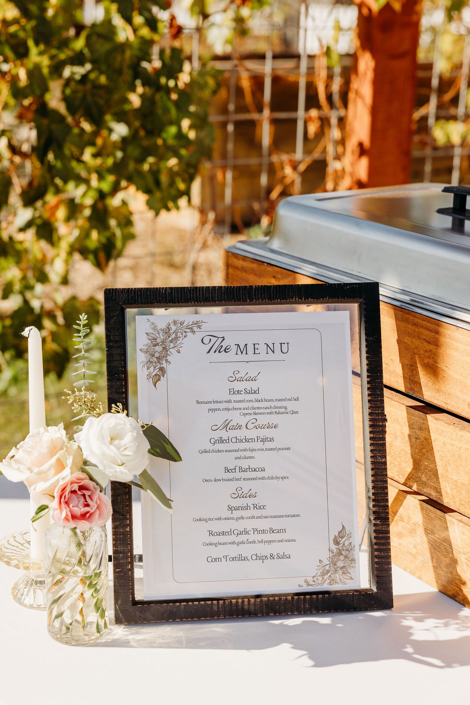 Elegant wedding menu cards in black frames displayed on wooden tables with floral decorations.