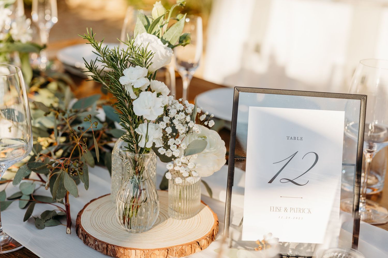 Elegant wedding table setting with floral centerpiece and table number on wood slice charger.