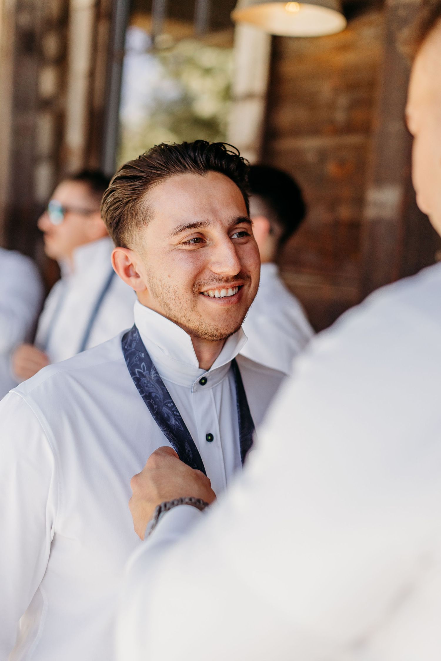 A joyful moment captured during wedding preparations with groomsmen in white attire.