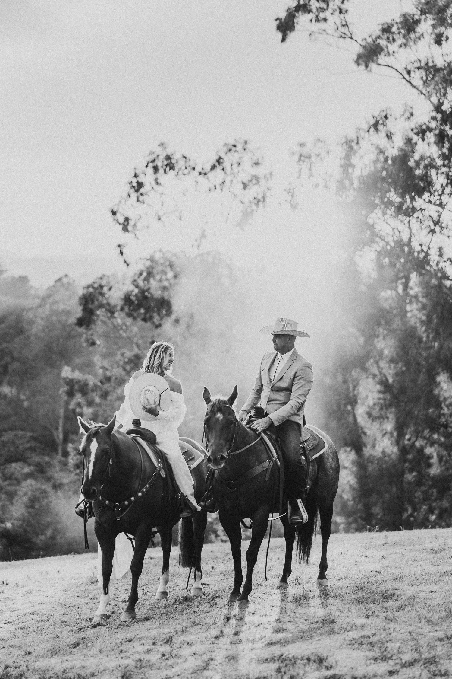 Black and white photograph of two riders on horseback having a conversation on a hillside.