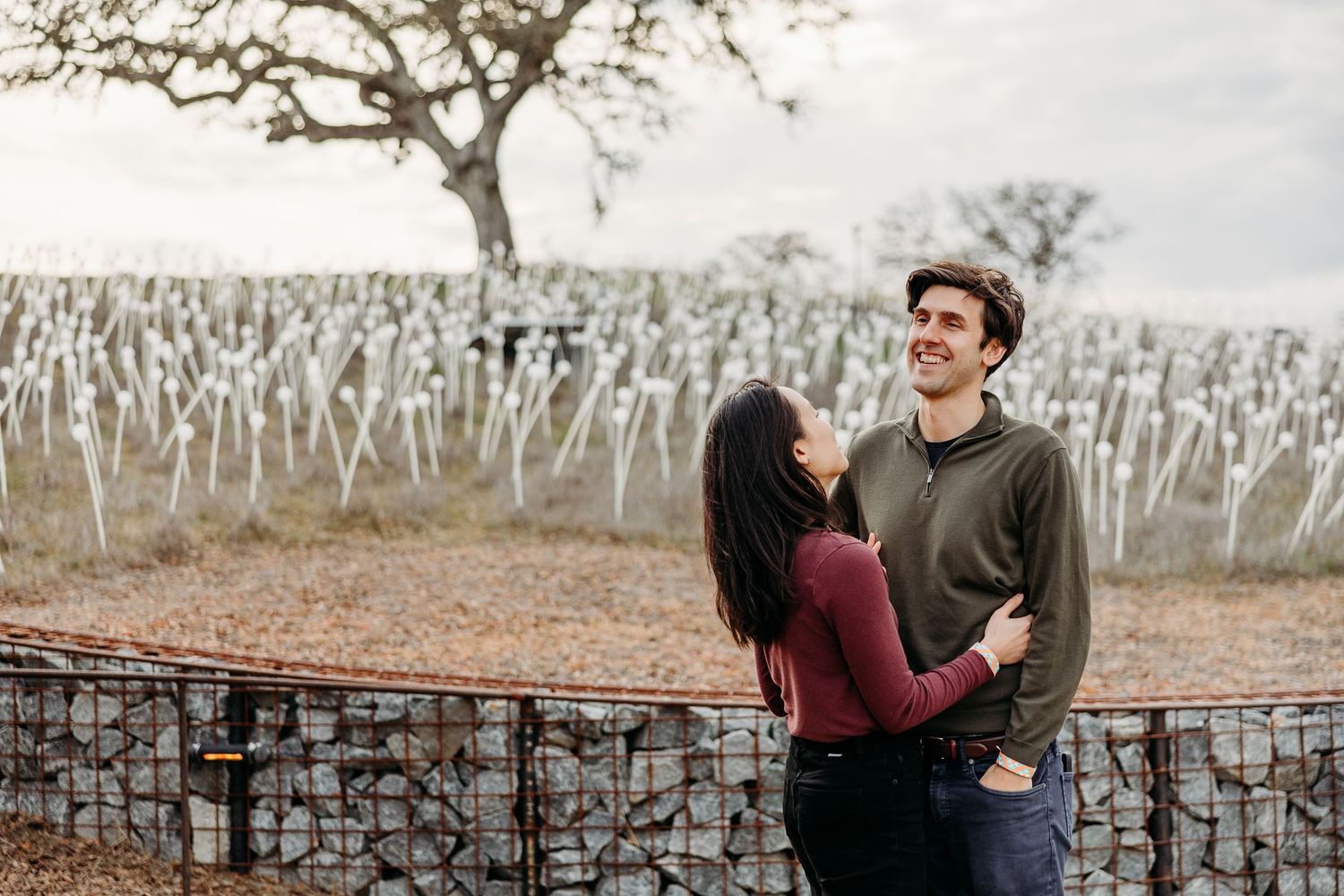 A couple walks together through a scenic vineyard on a misty winter day.