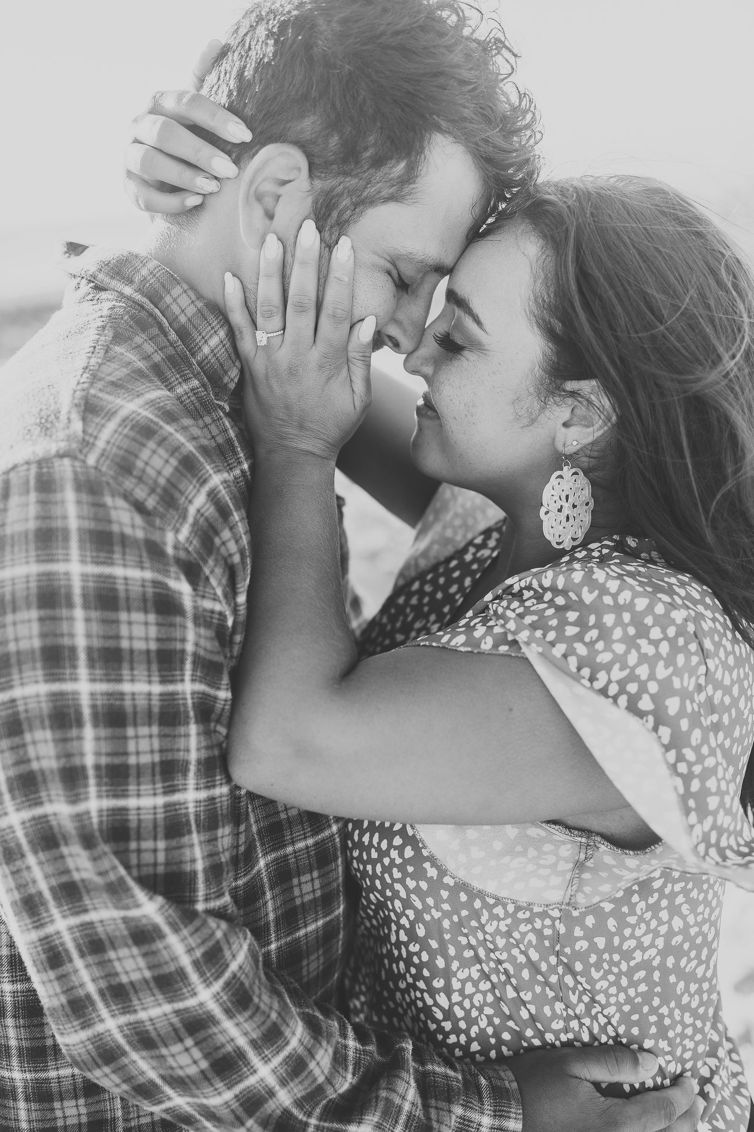 Black and white portrait of couple in tender embrace with woman wearing statement earrings.
