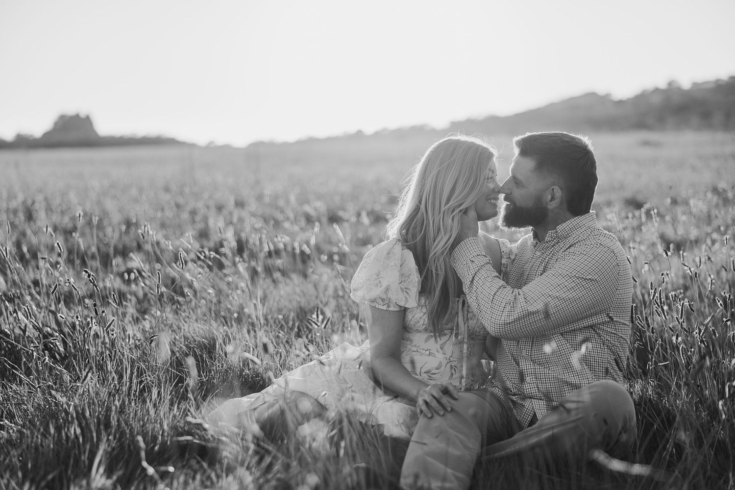 Romantic couple embracing in golden wheat field at sunset creating silhouette against warm sky.