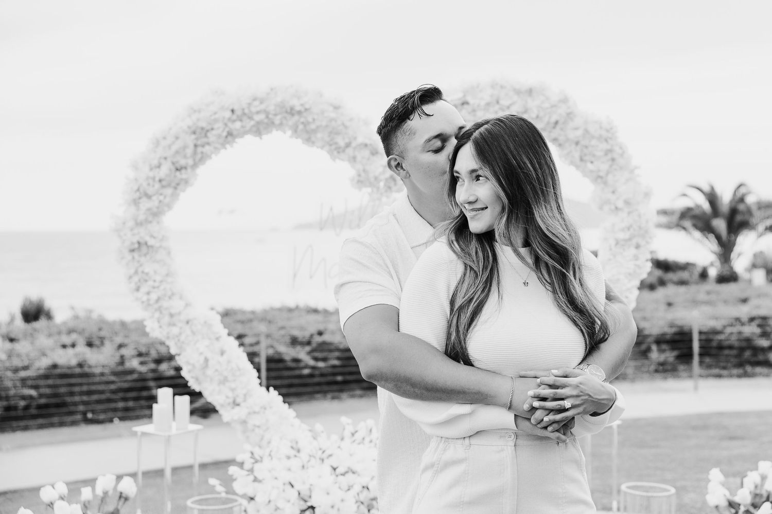 Black and white photo of a couple embracing during their outdoor wedding ceremony.