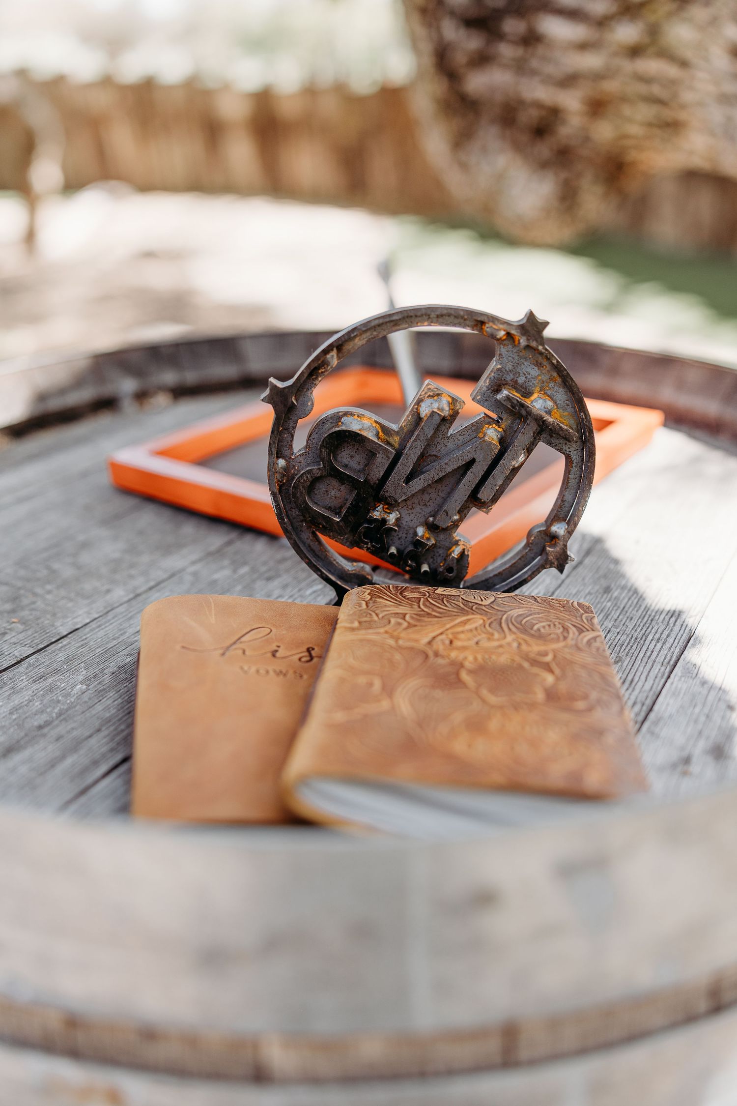 A vintage camera and leather journals arranged on a rustic wooden barrel surface.
