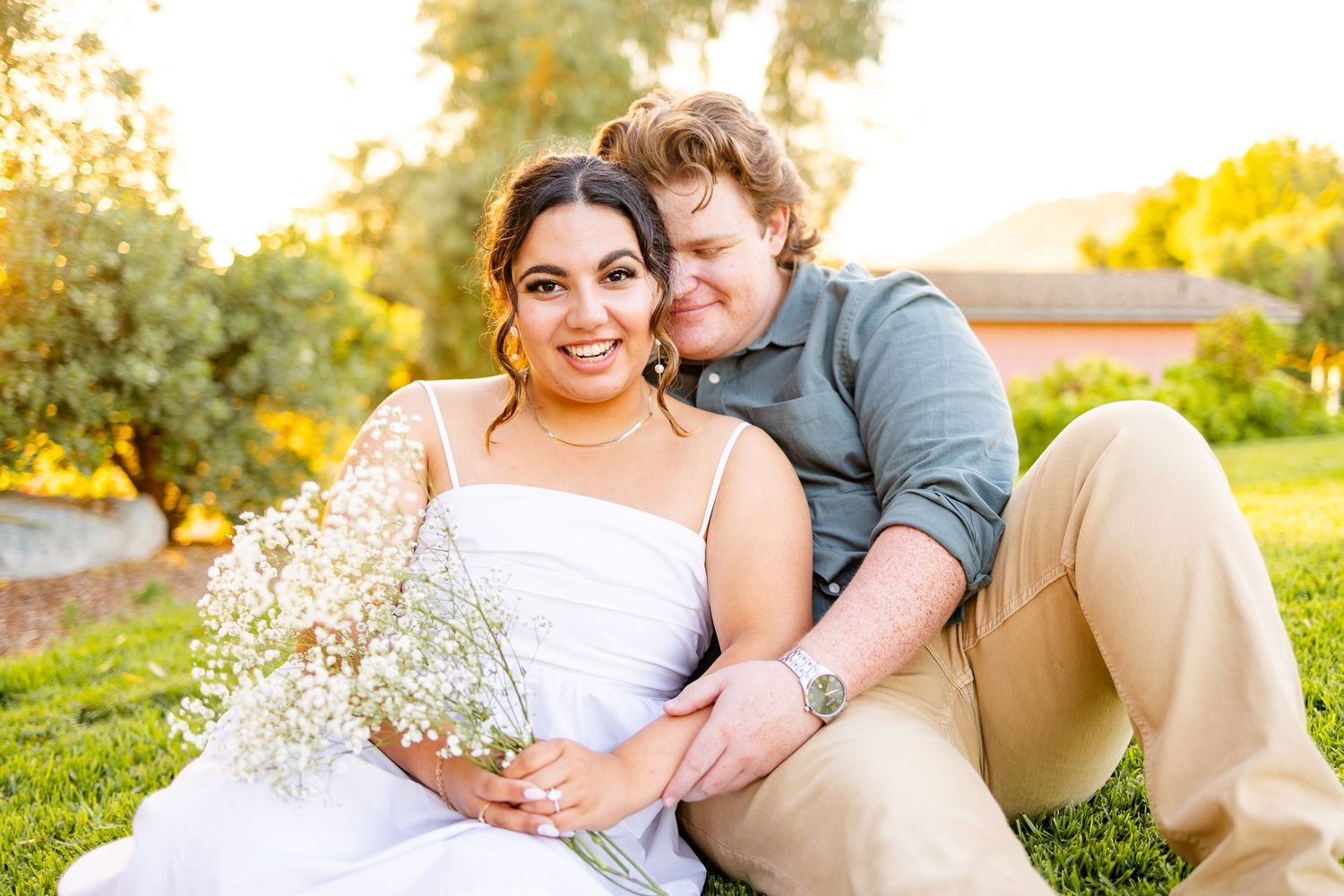 Couple poses with baby's breath flowers during outdoor sunset photo session.