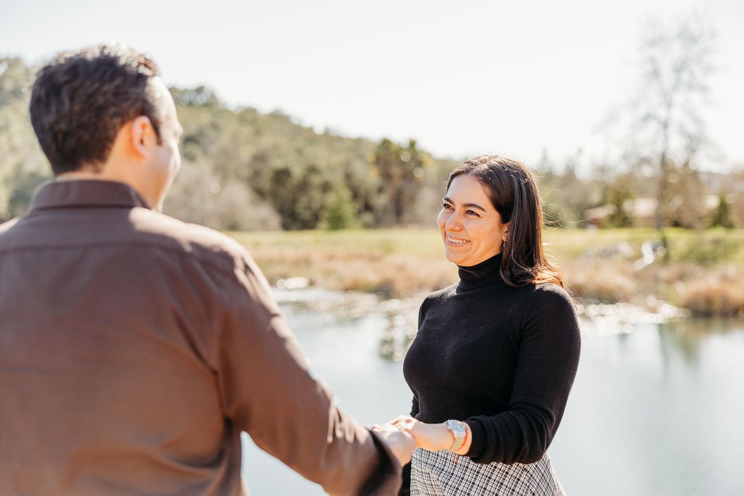 A couple enjoys a tender moment together by a scenic lakeside setting.