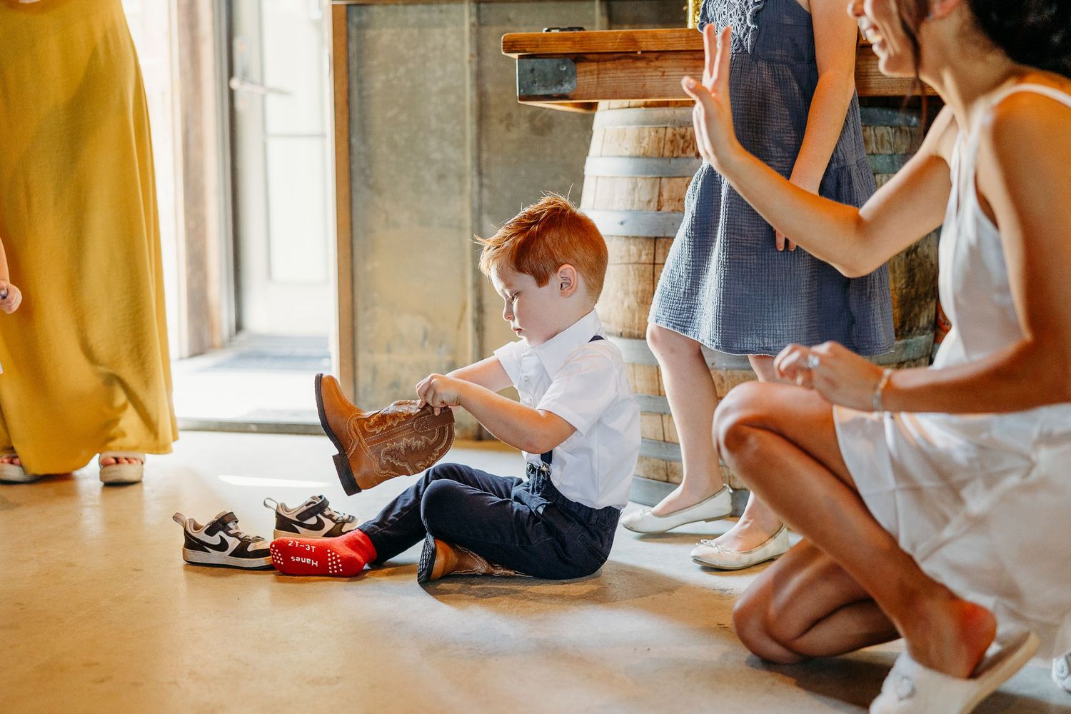 Feet of people sitting in a casual setting against a white wall with warm lighting.